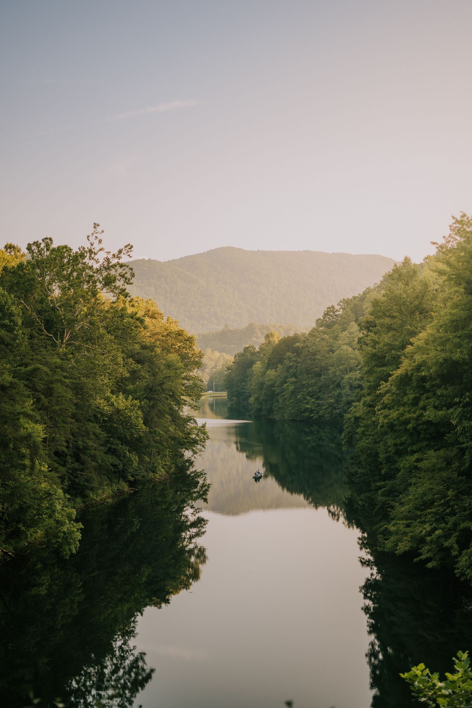 Serene mountain lake landscape with tree-lined shores at sunset.