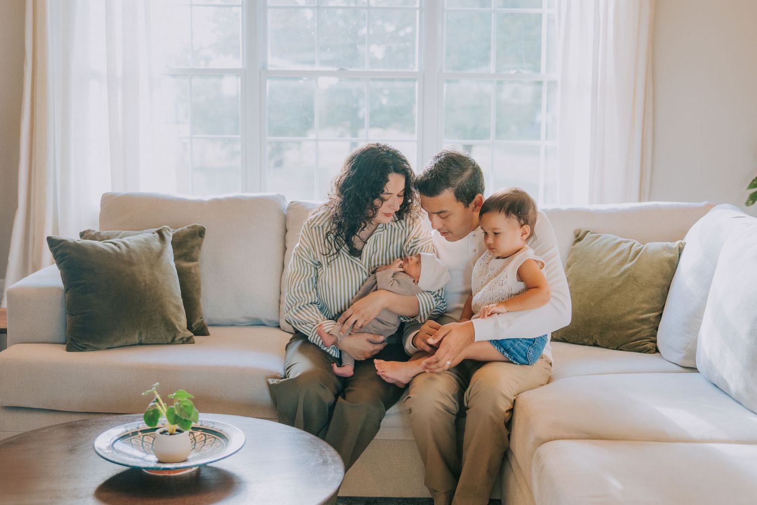 A family shares a quiet moment together on a cozy gray sofa in their living room.