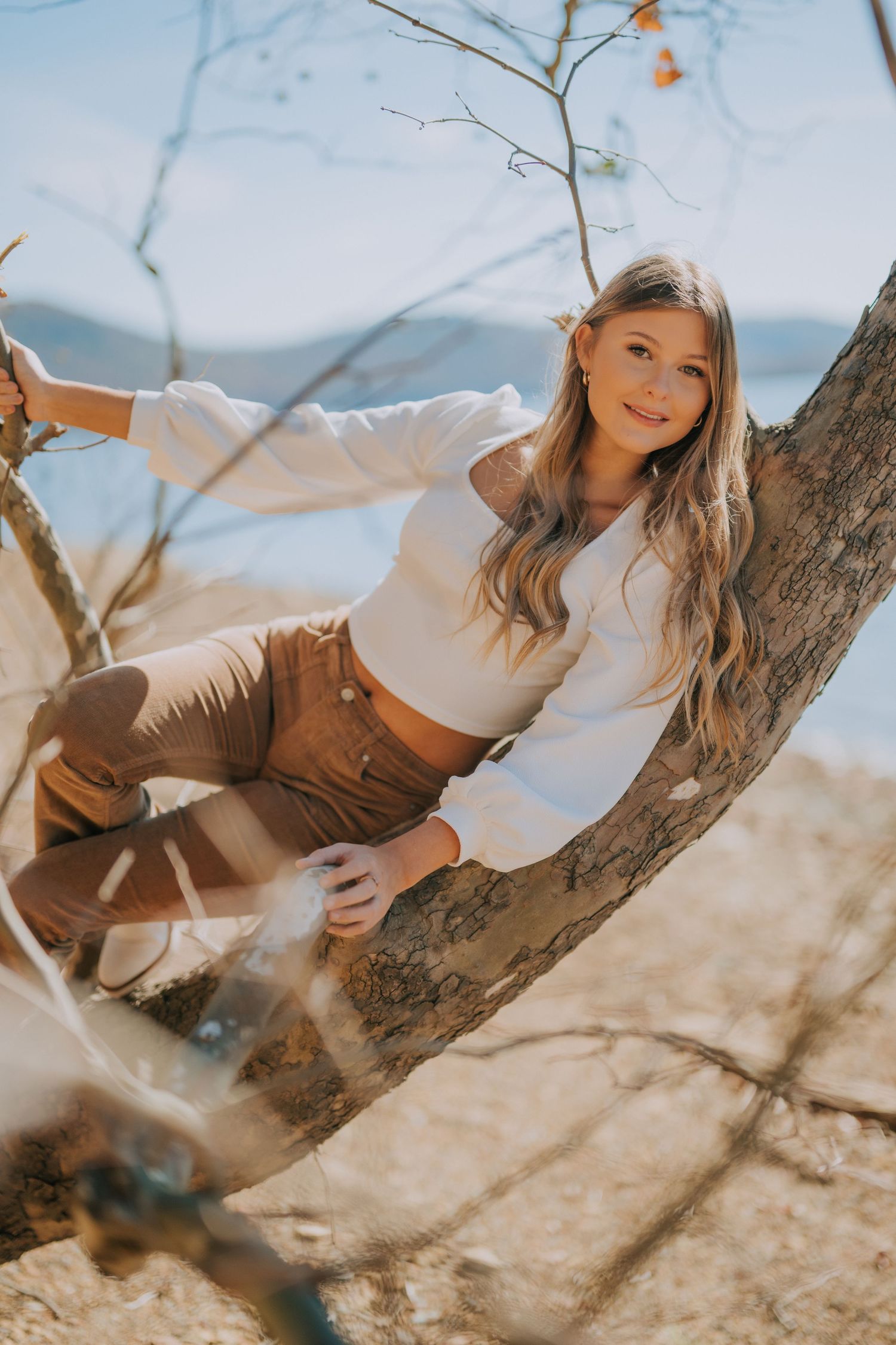 Casual outdoor portrait against a tree branch in natural sunlight.