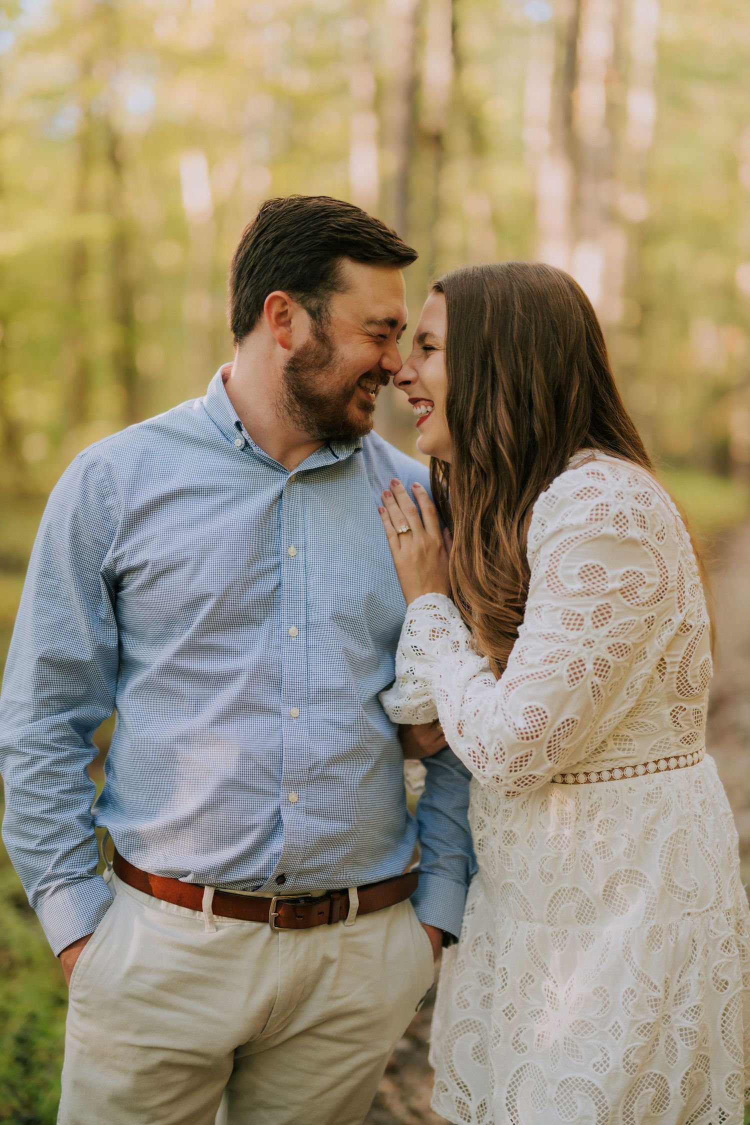 Couple in casual attire shares tender moments in sunlit forest setting.