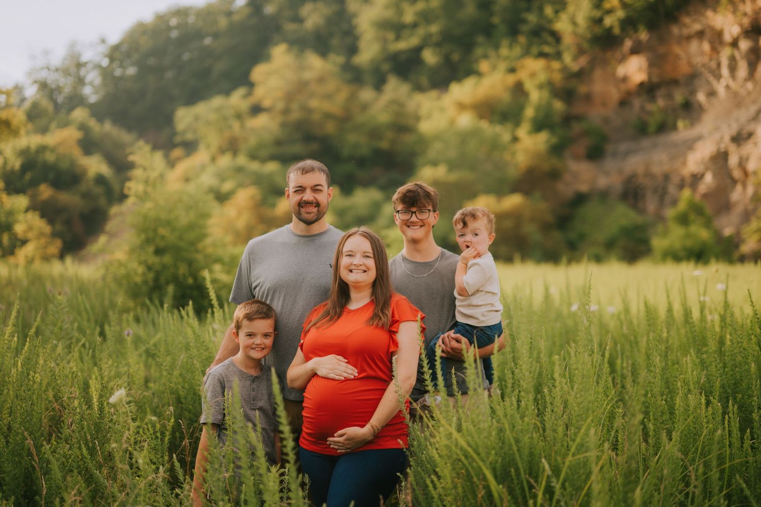 Family portrait session in golden sunset meadow with tall grass.