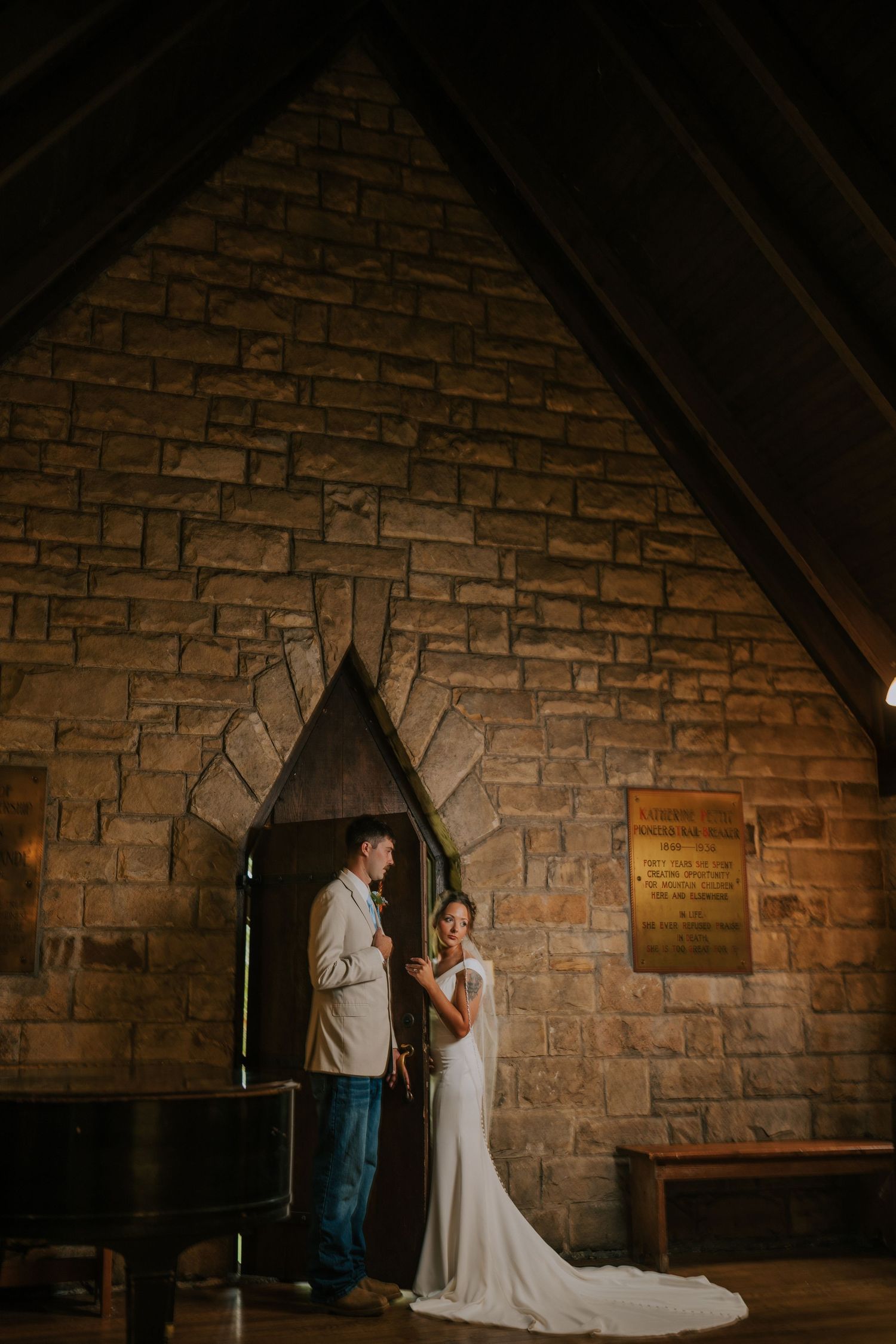 A wedding couple sharing an intimate moment inside a rustic stone chapel with dramatic lighting.