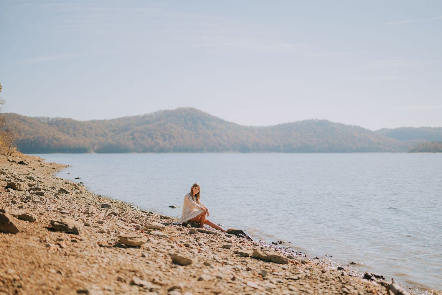 Scenic lakeside landscape with rocky shoreline and mountain backdrop.