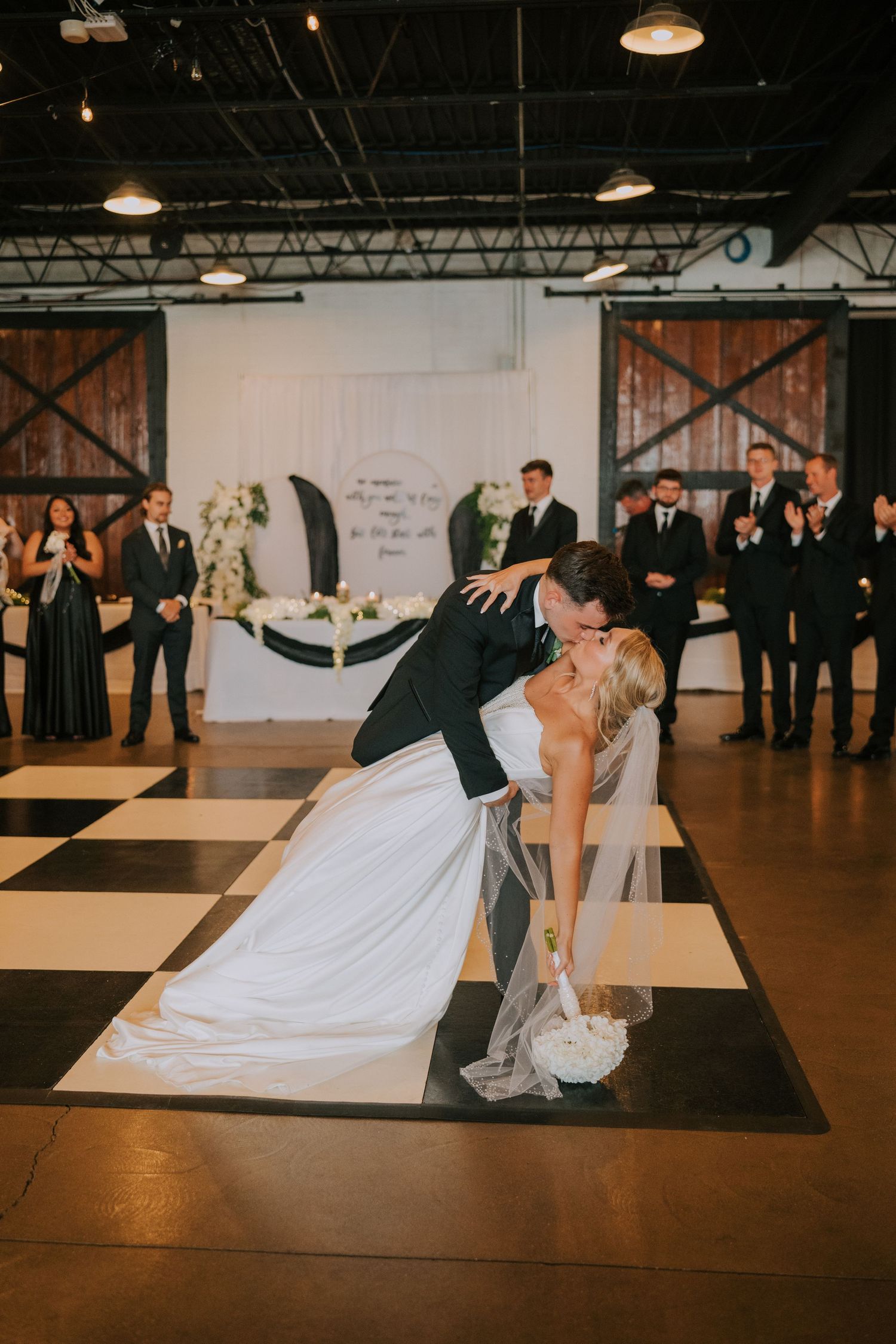 A dramatic wedding dance dip on a dark wooden dance floor.