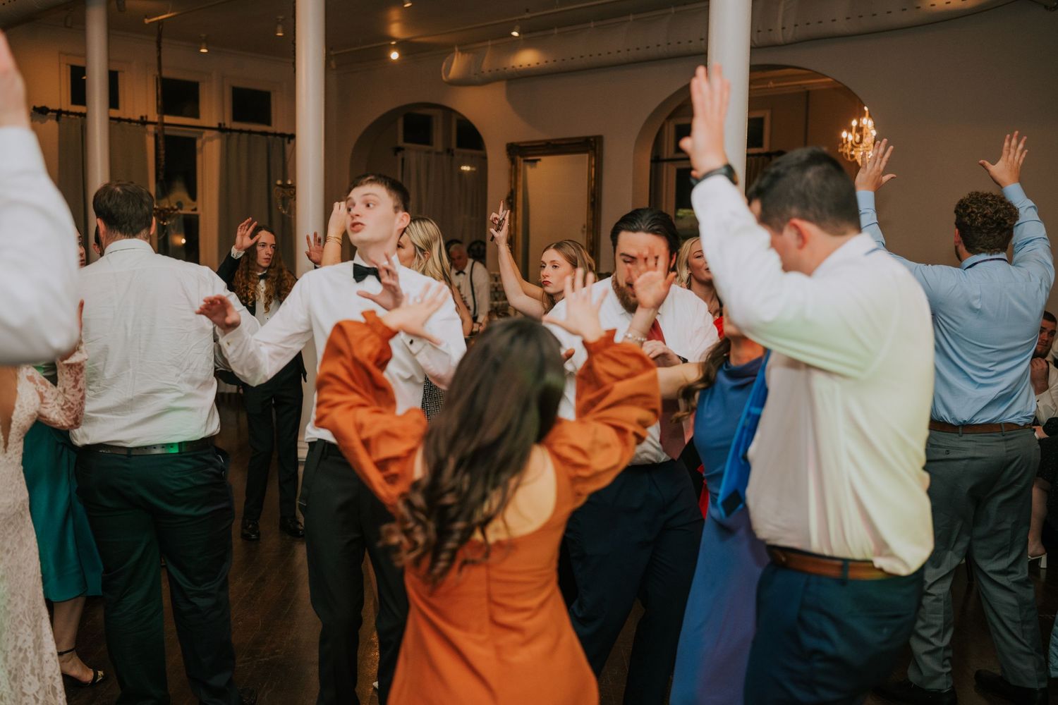 Wedding reception dance floor filled with guests celebrating and dancing.