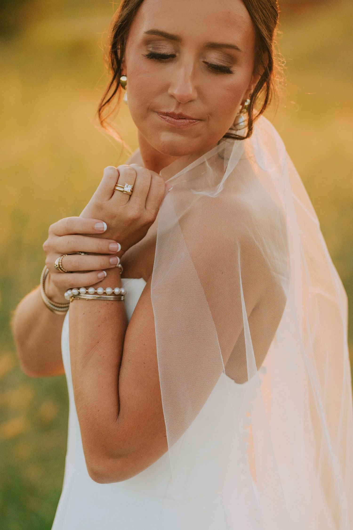Close-up of bridal jewelry and veil details in warm sunset lighting.