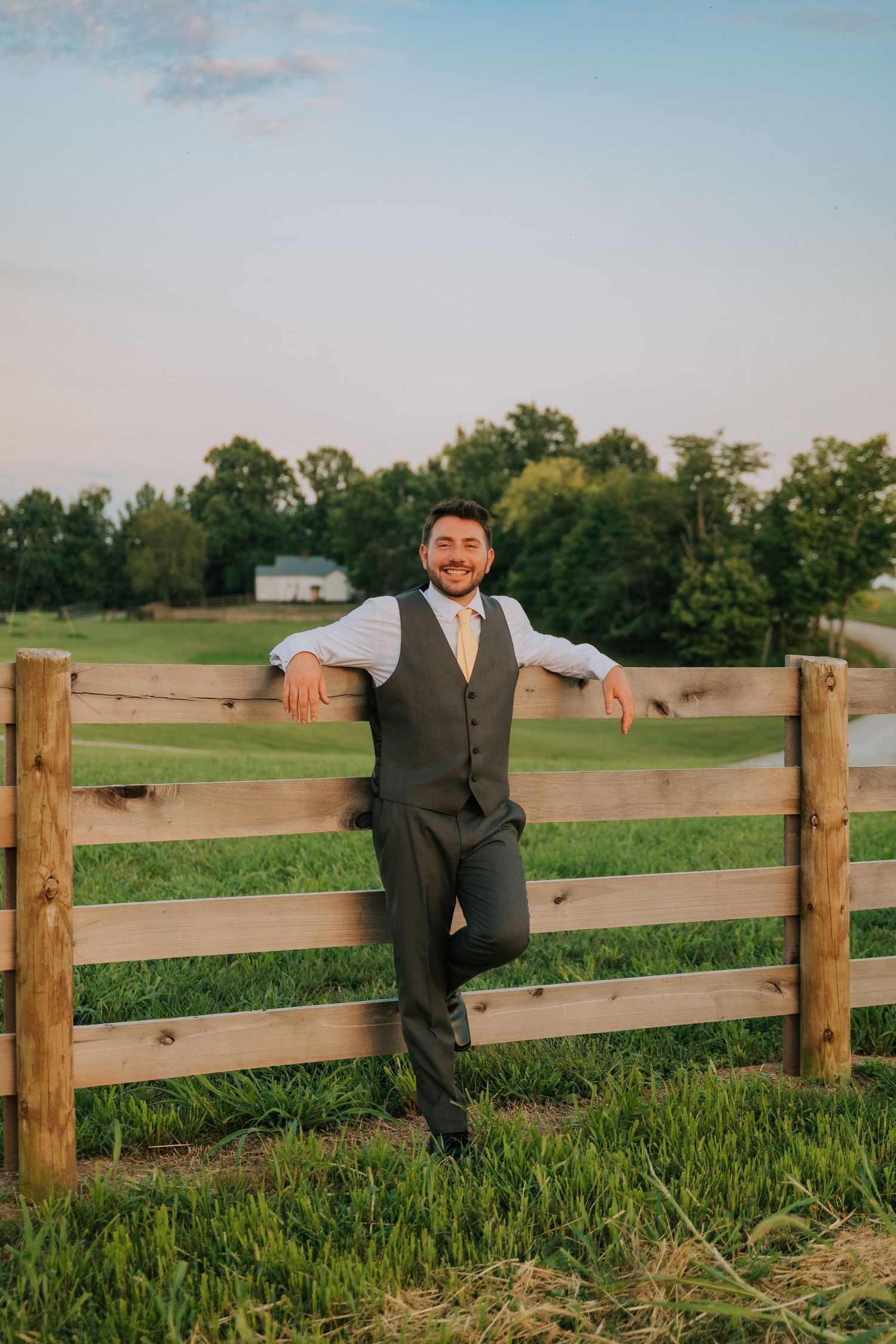 Casual portrait by a wooden fence in a countryside setting.
