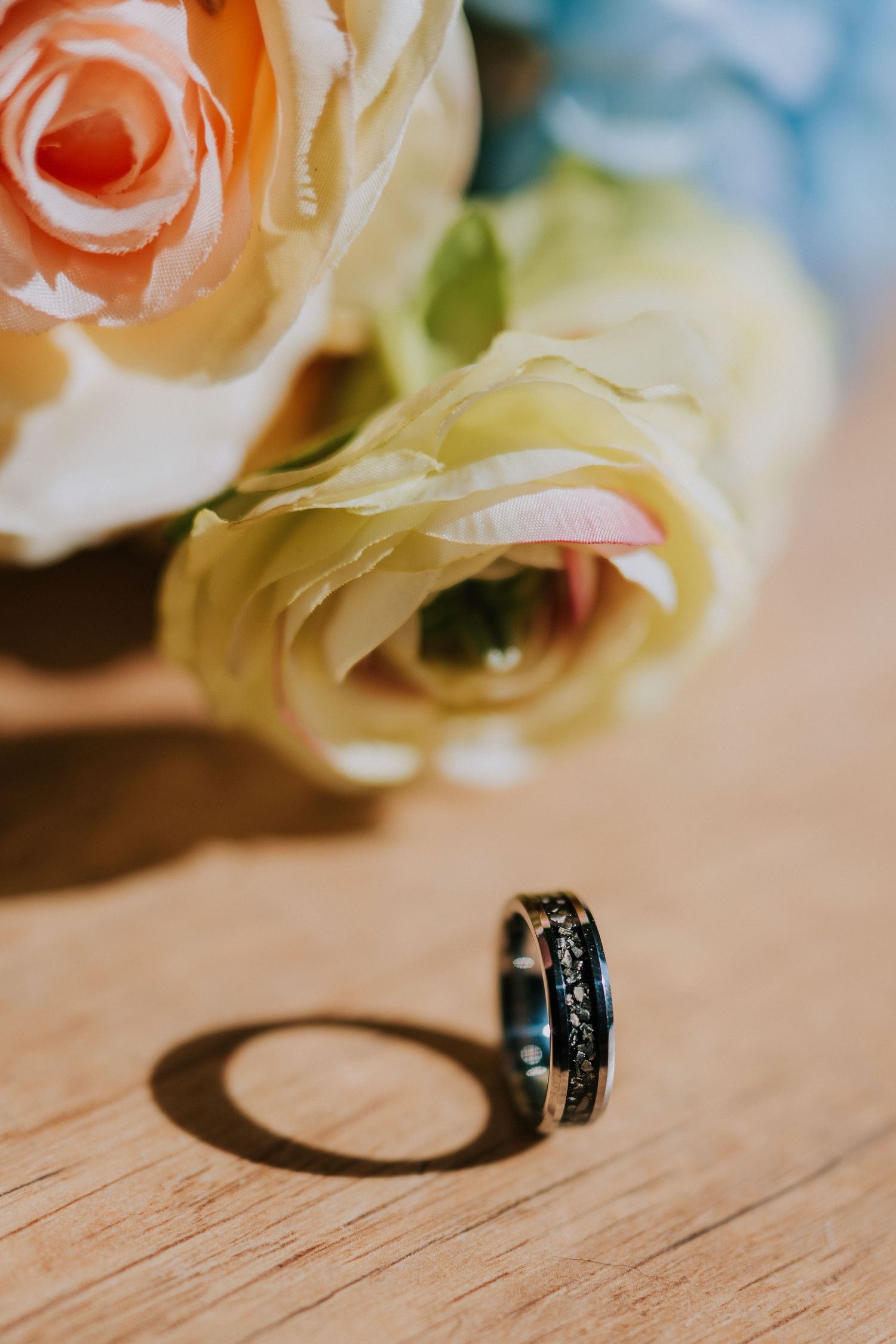 Wedding rings photographed with soft focus roses in the background.