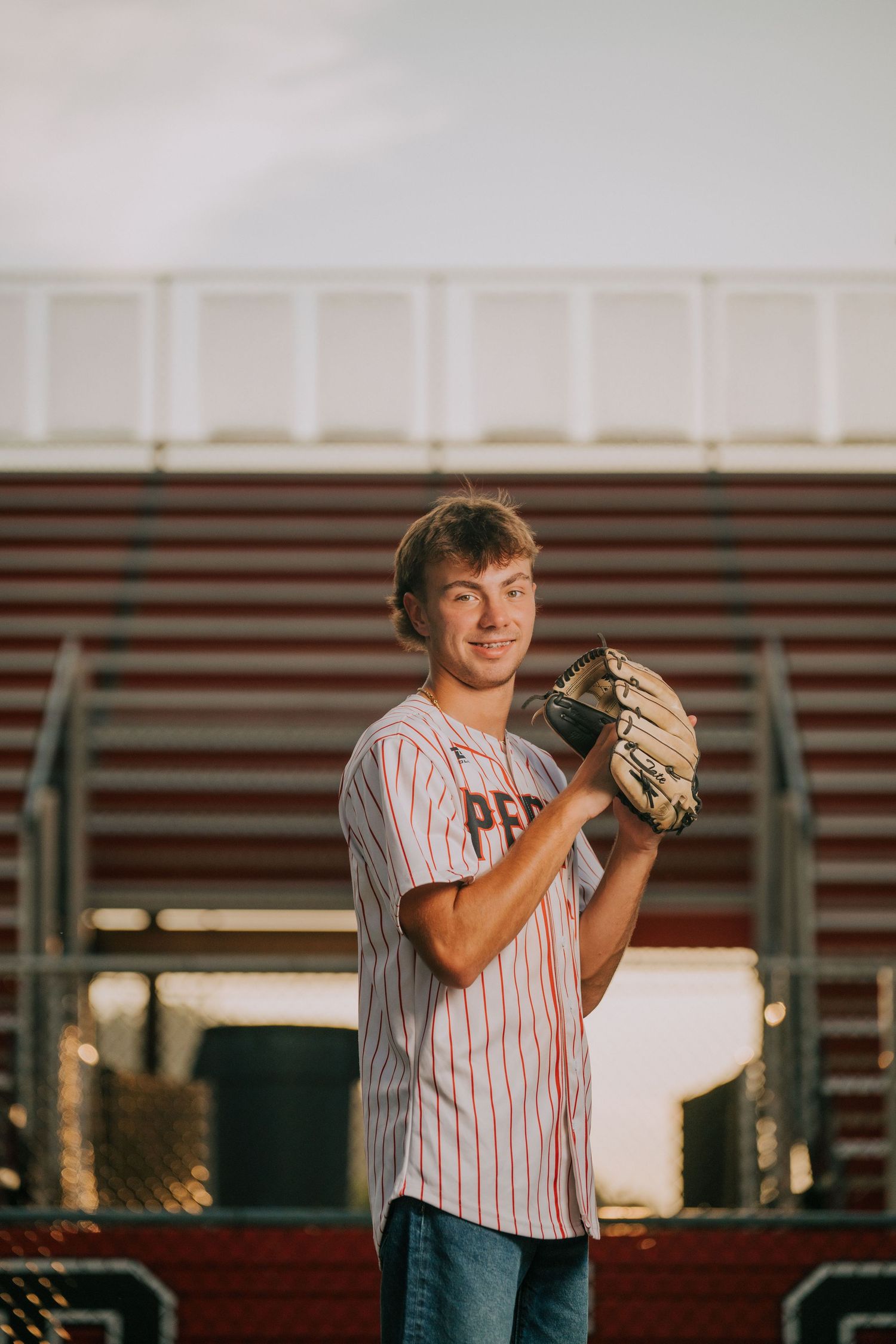 Baseball player in pinstriped uniform practices pitching stance at stadium.