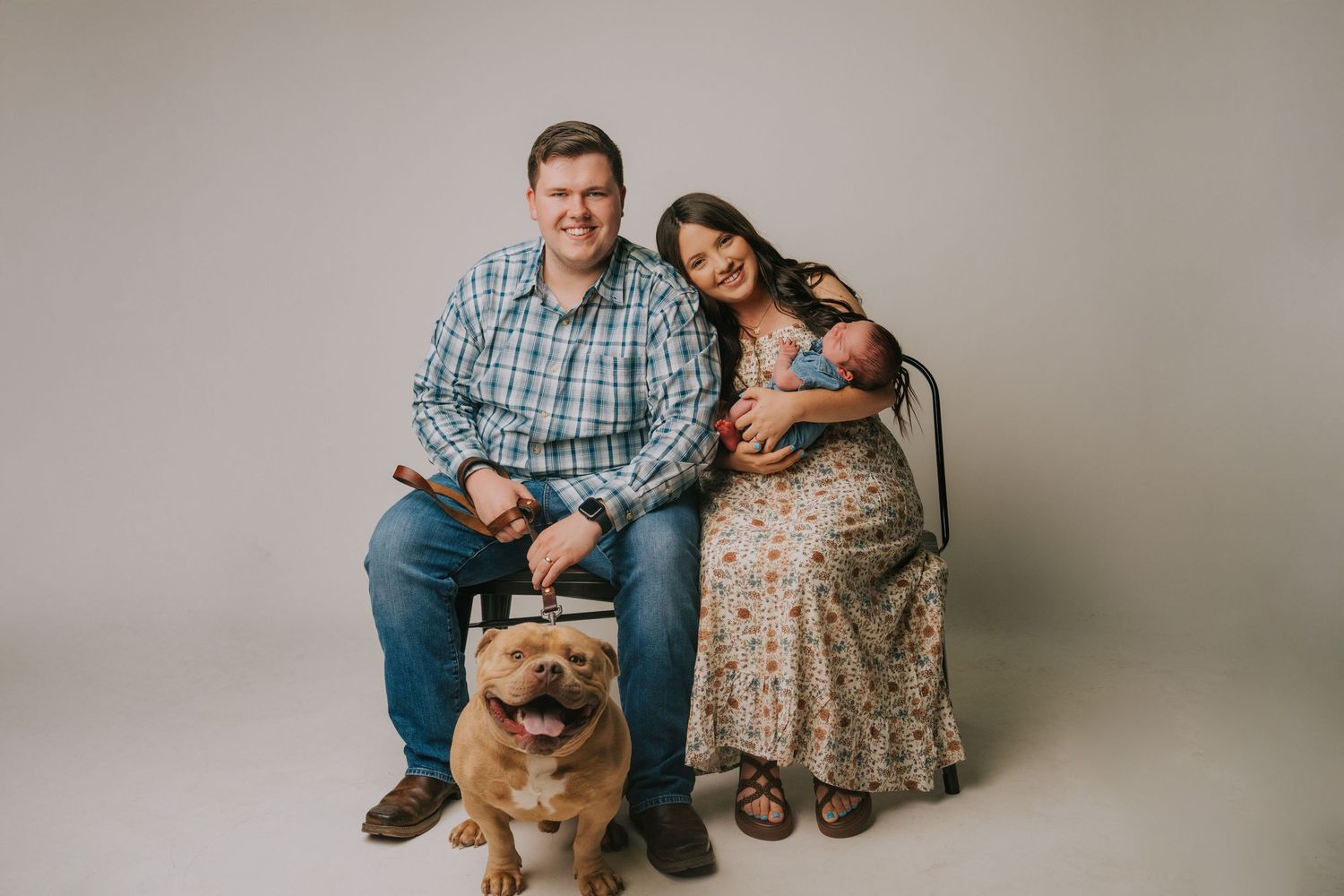 Family portrait with dog in studio against neutral background.