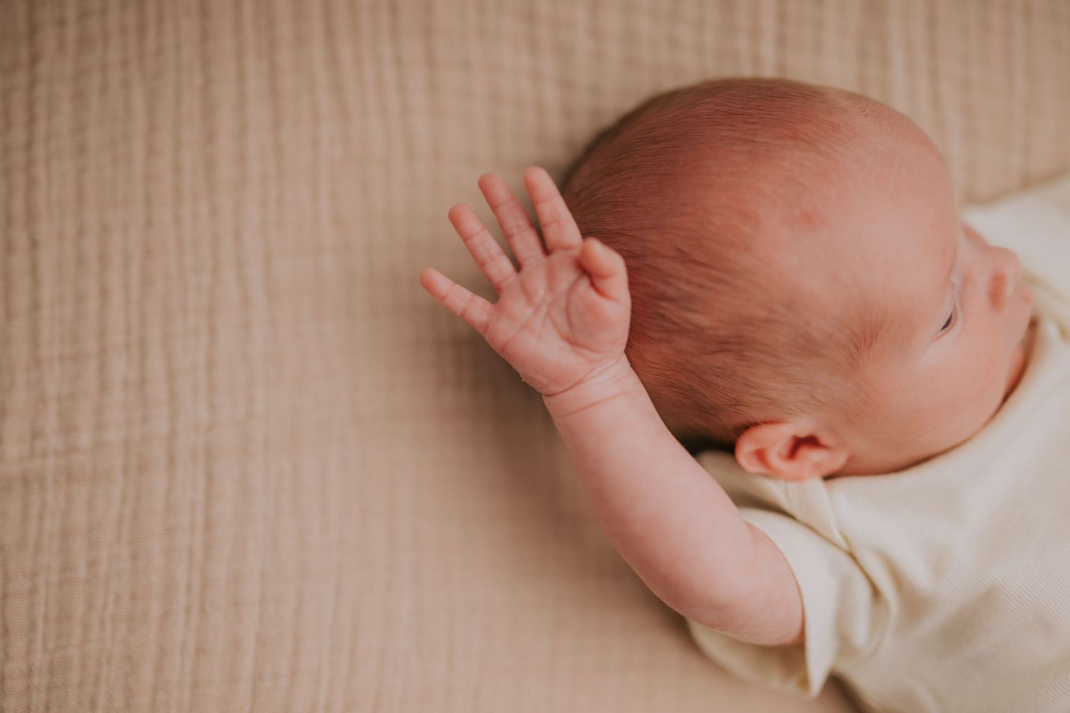 Close-up shots of a newborn baby on a textured beige background.