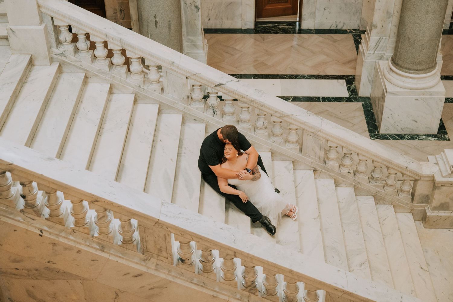 A white marble staircase with ornate balusters in an elegant building interior.