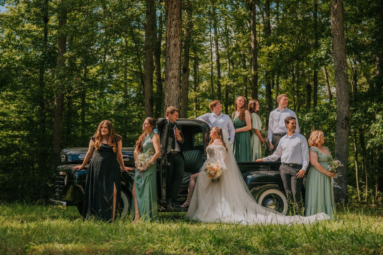 Wedding party celebrates in a lush green forest setting during golden hour lighting.