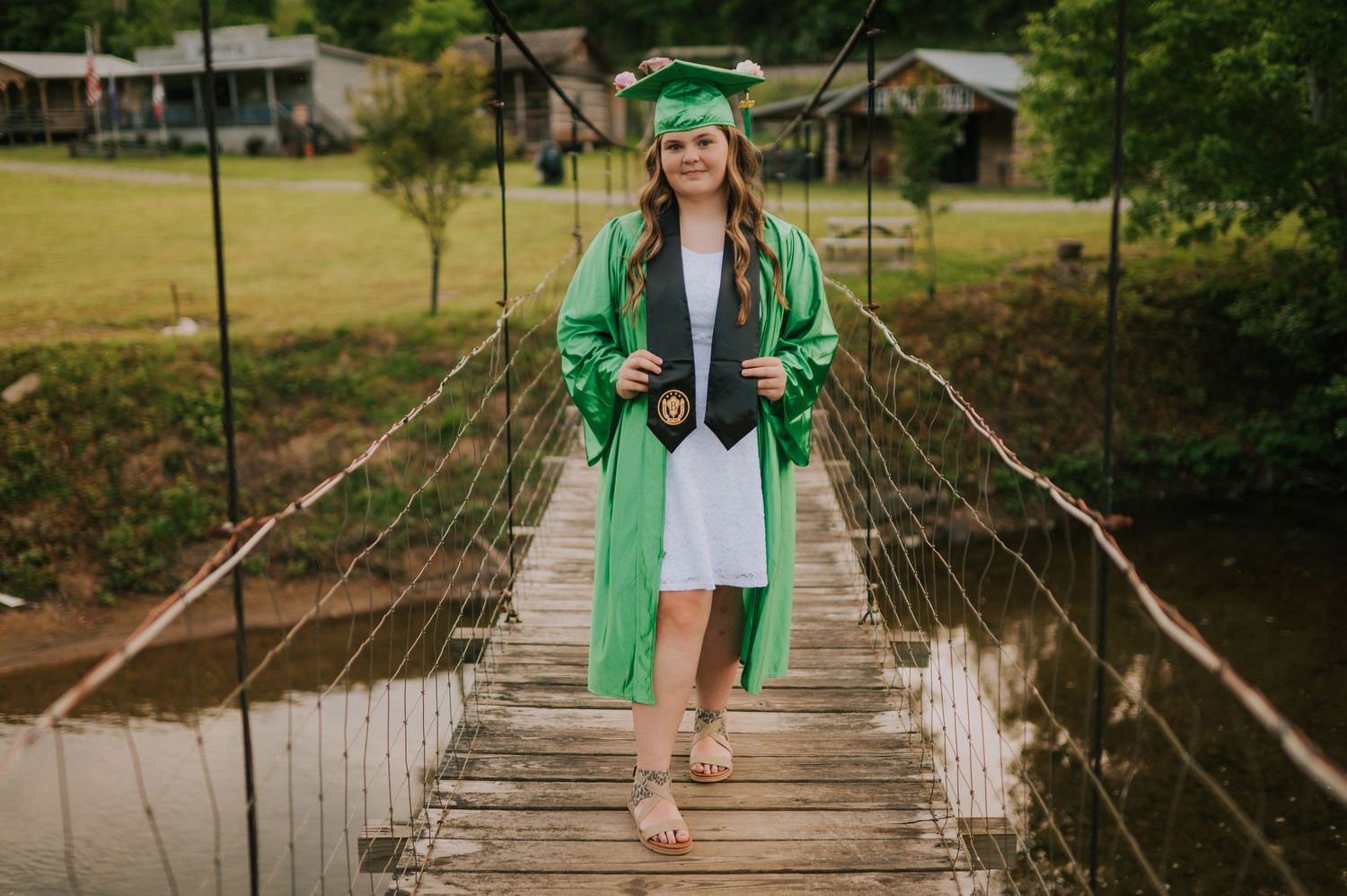 A person crosses a rustic rope bridge over water while wearing green.