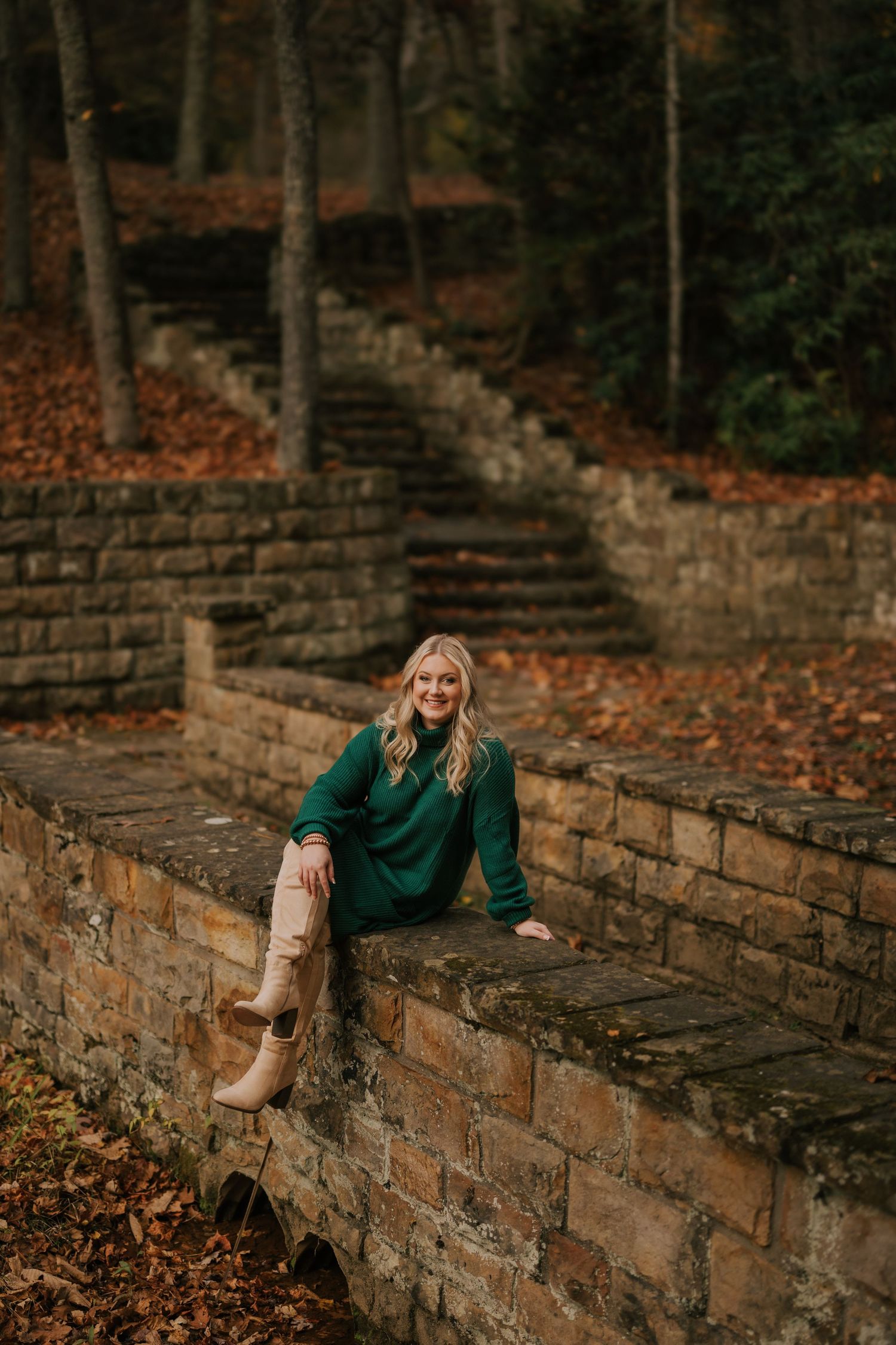 Historic stone wall steps surrounded by fallen autumn leaves in a wooded setting.