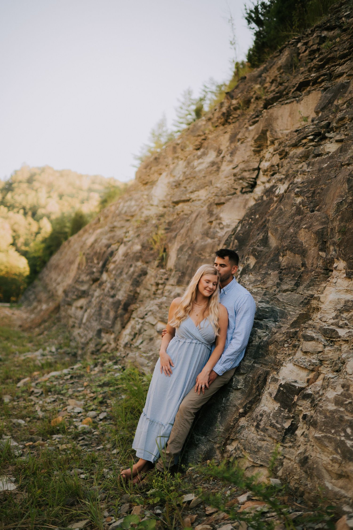 A romantic portrait against a dramatic rocky cliff face in natural outdoor lighting.