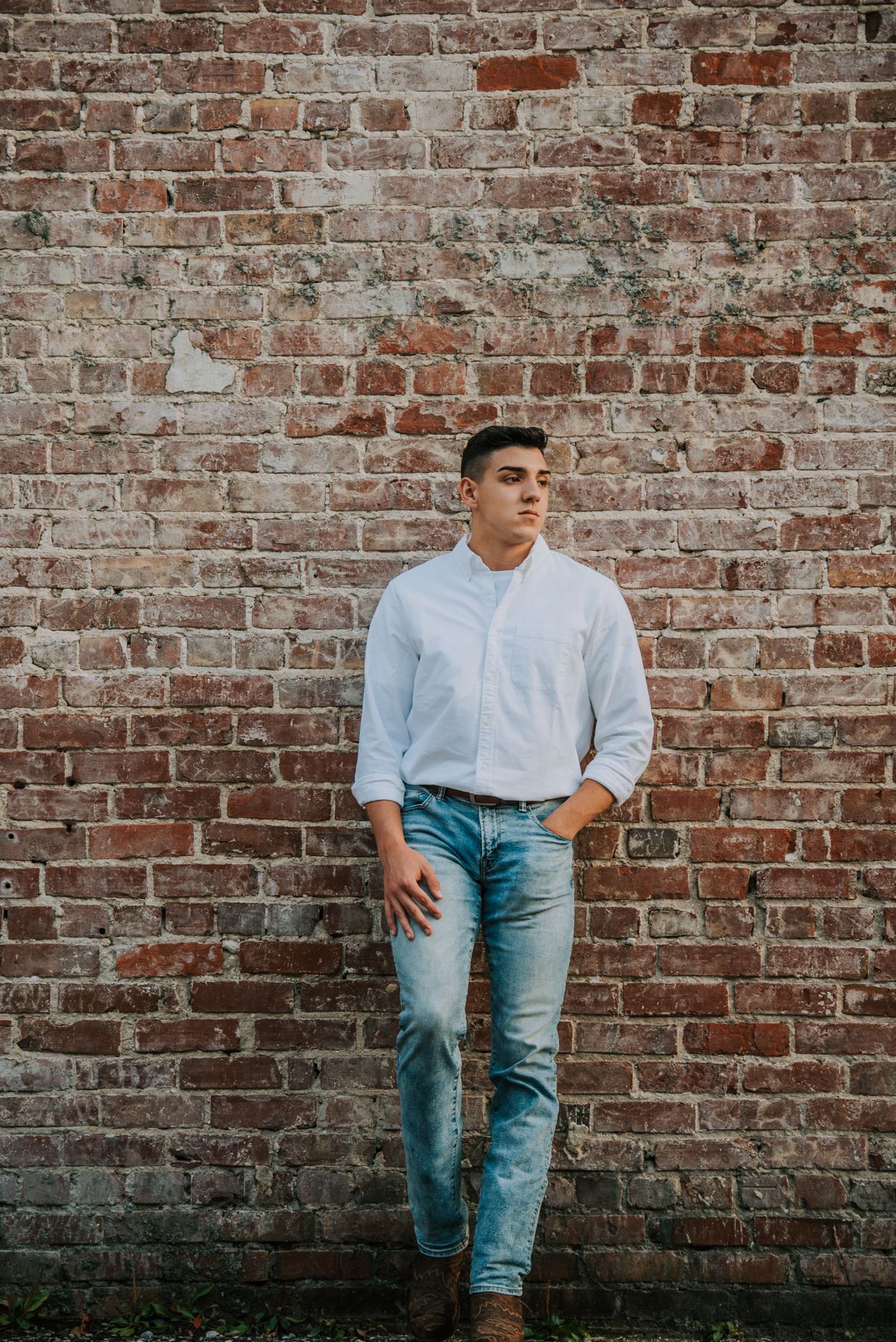 A casual portrait session against a weathered brick wall background.