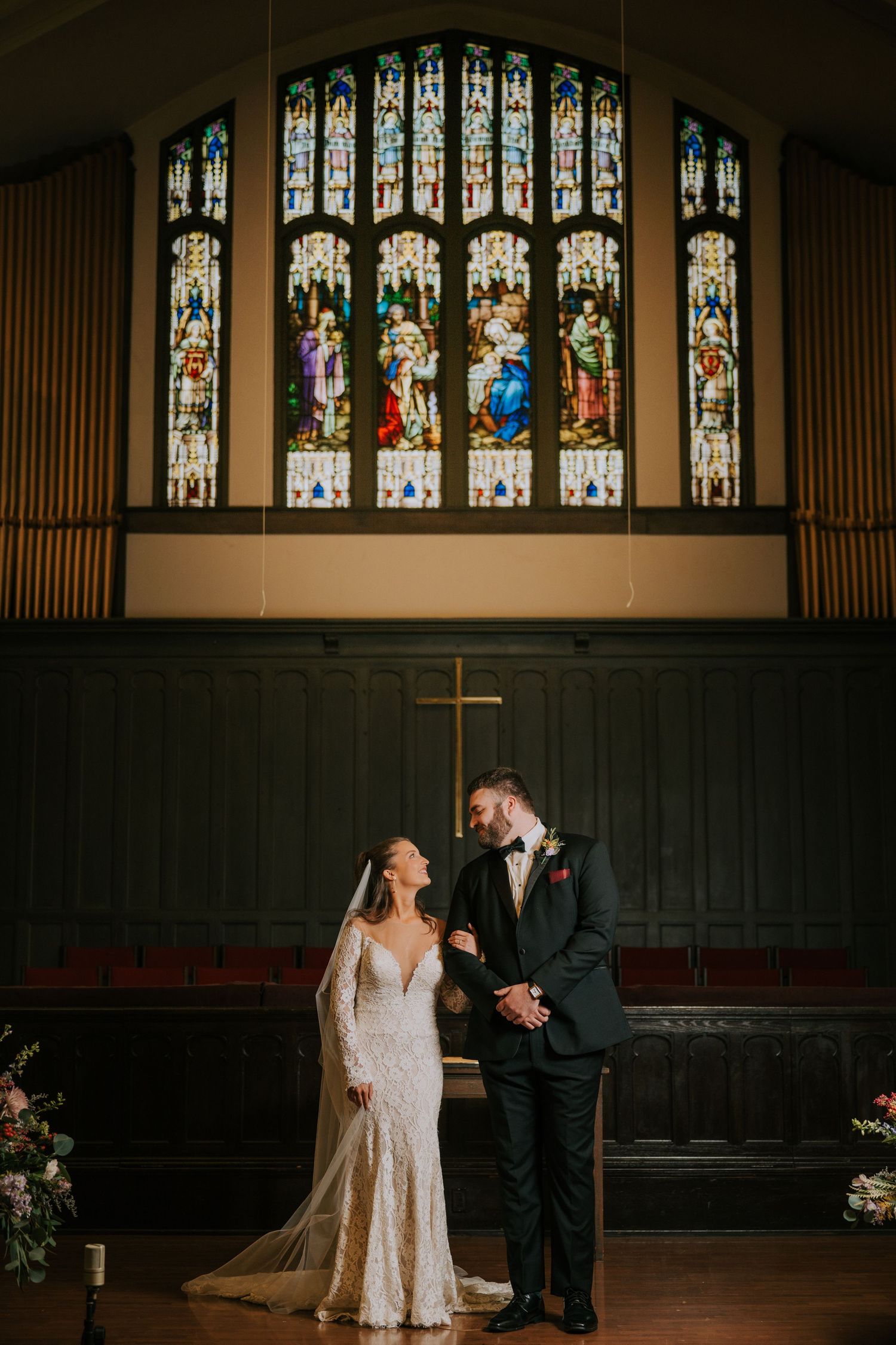 Church wedding scene with ornate stained glass windows and elegant decor.