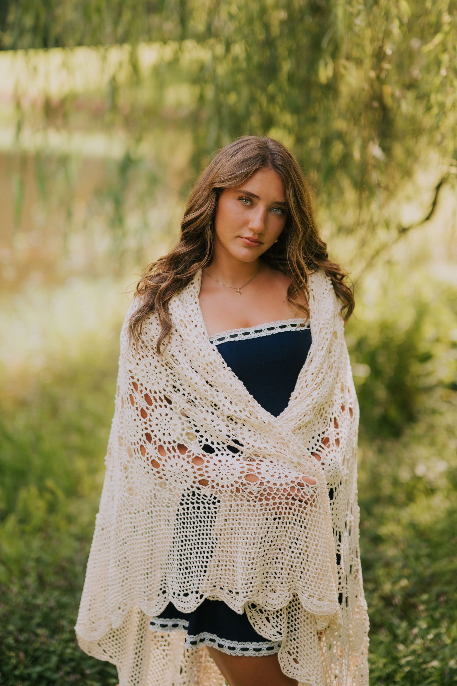 A delicate lace shawl drapes elegantly over dark clothing against a soft natural background.