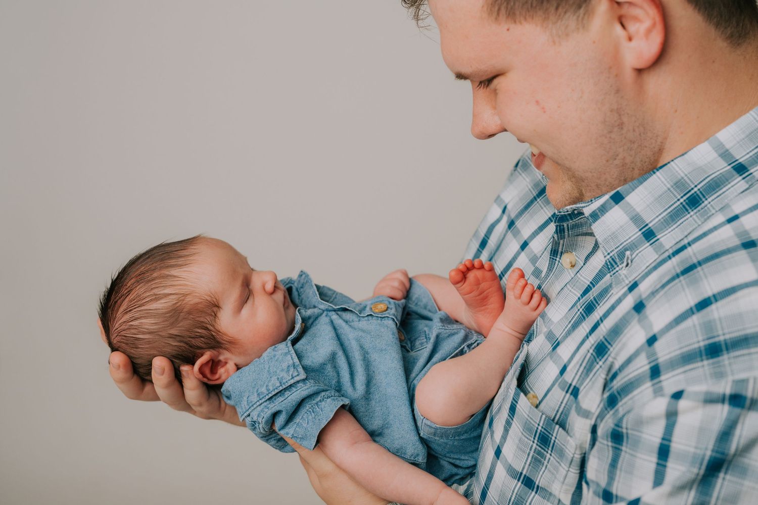 Tender newborn photography session with baby in blue outfit.