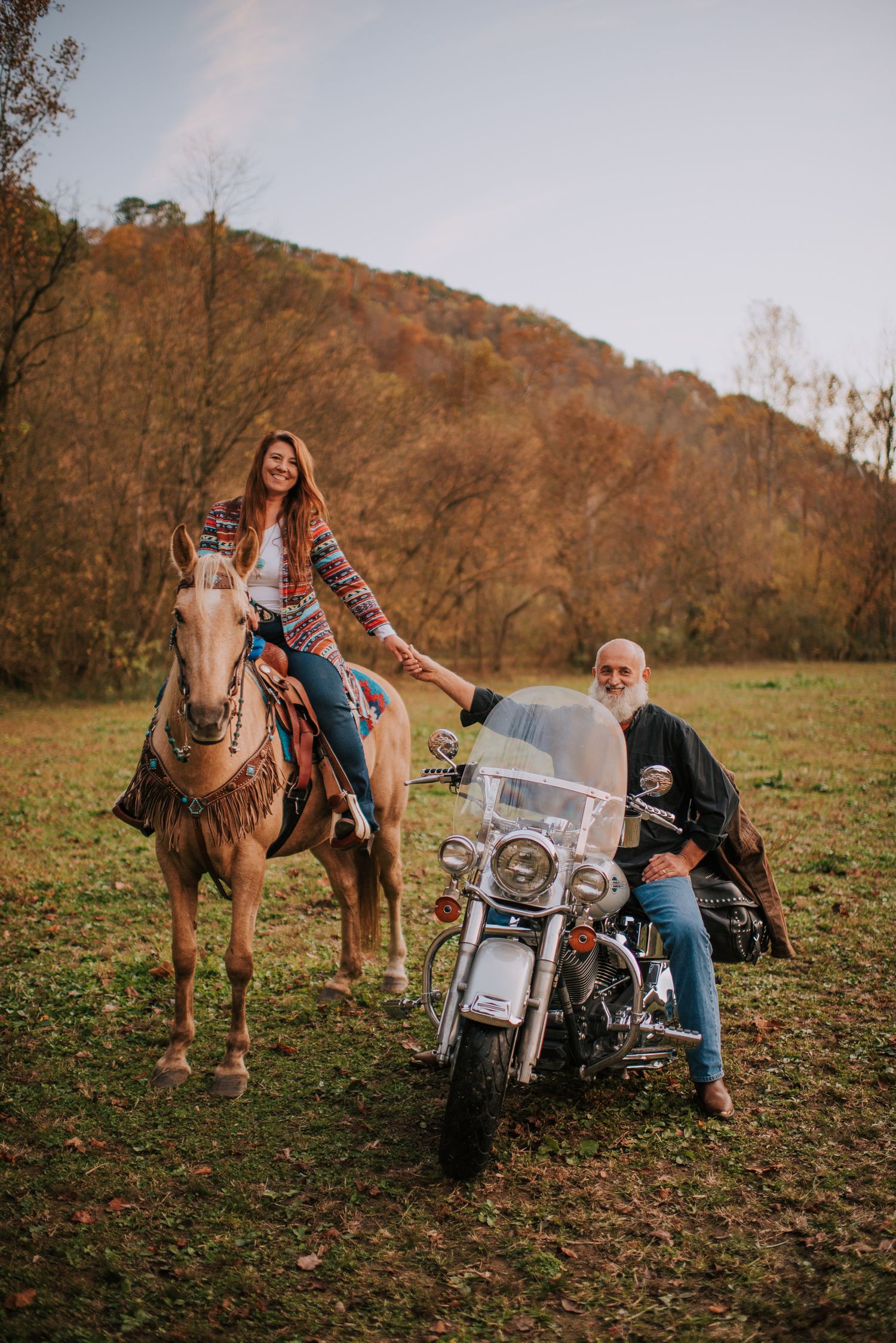 A casual photoshoot with horses and a motorcycle in a rustic autumn setting.