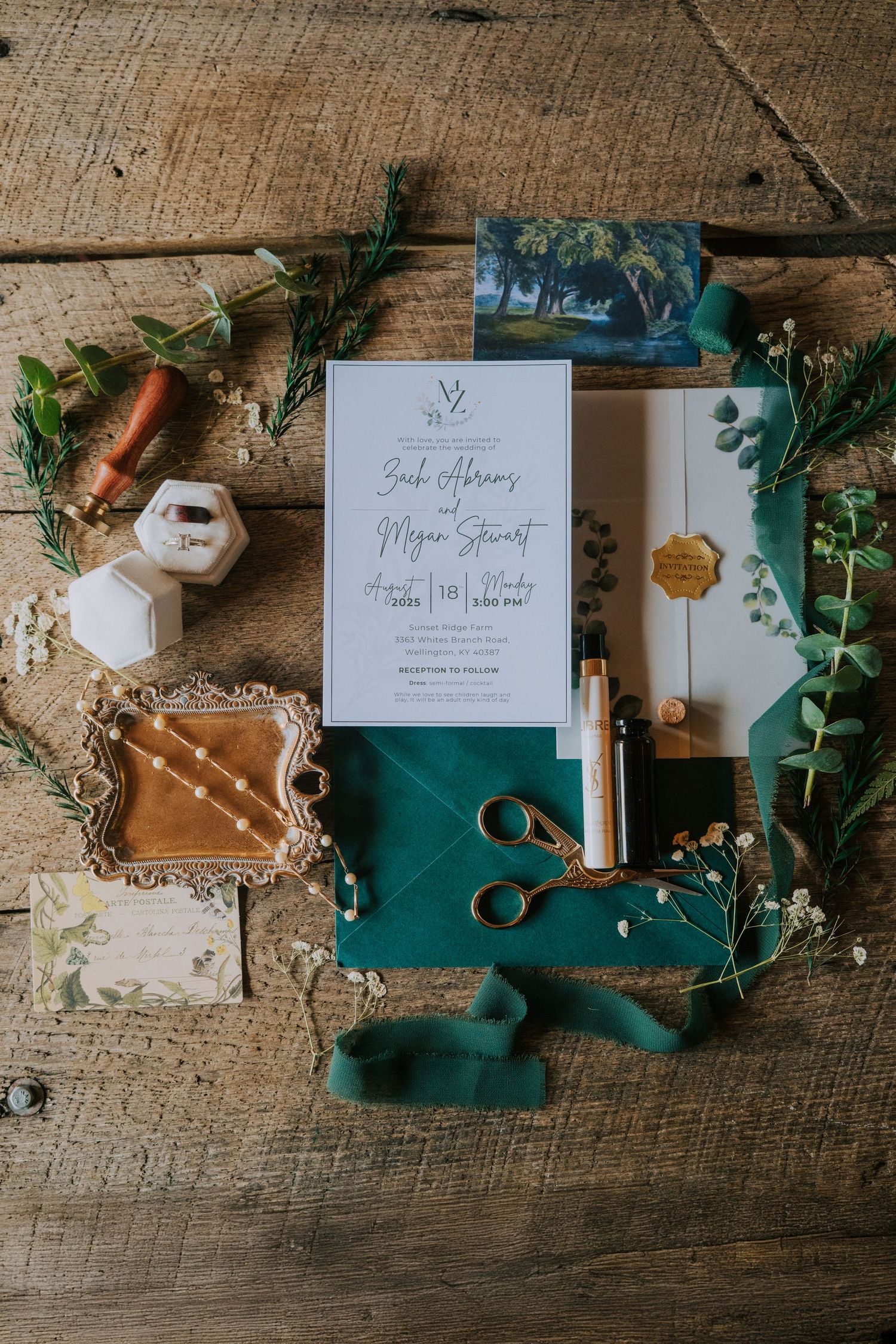 Elegant wedding invitation with emerald green ribbon, scissors, and greenery on rustic wooden background.