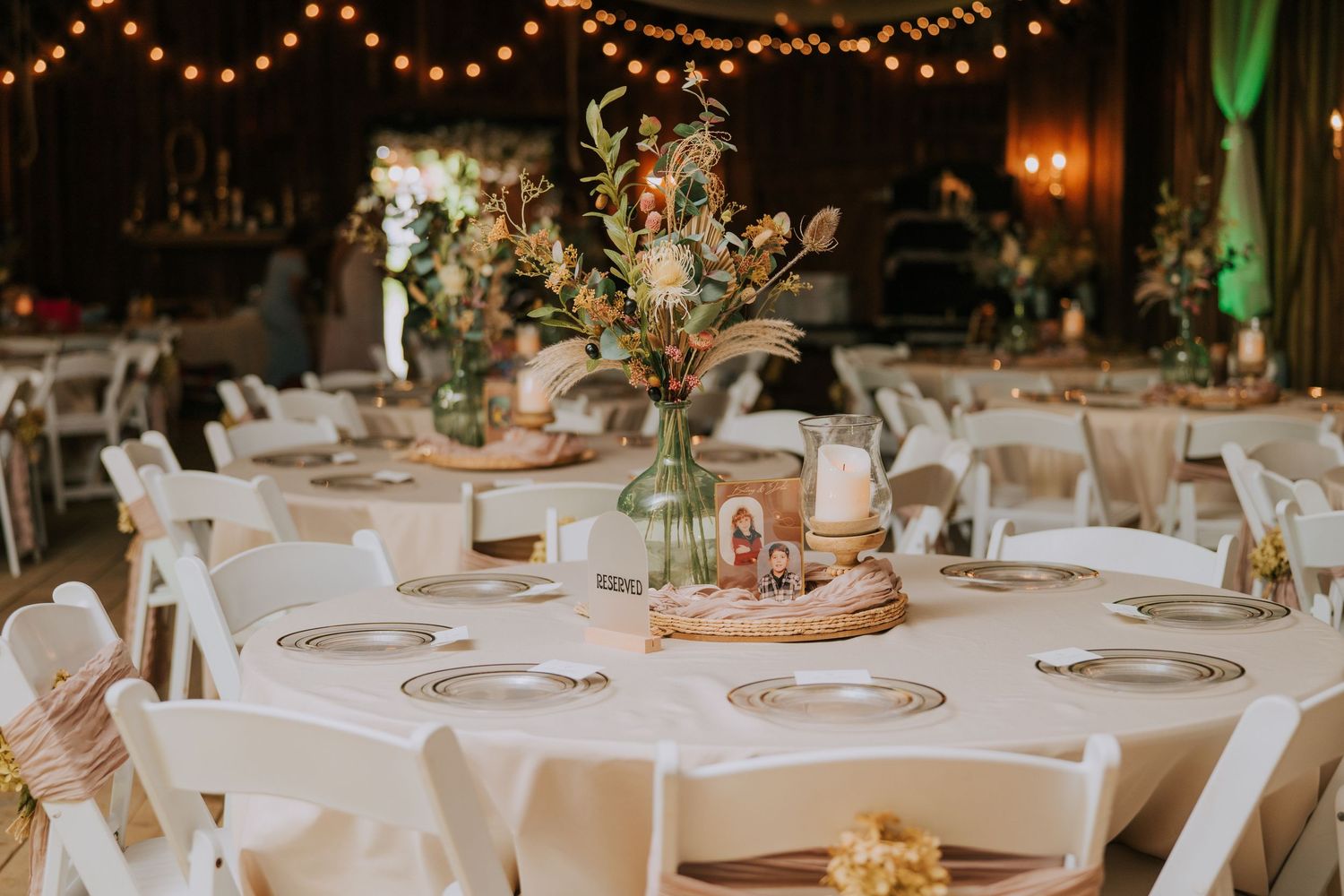 Elegant wedding reception tables set with white linens under romantic string lights.