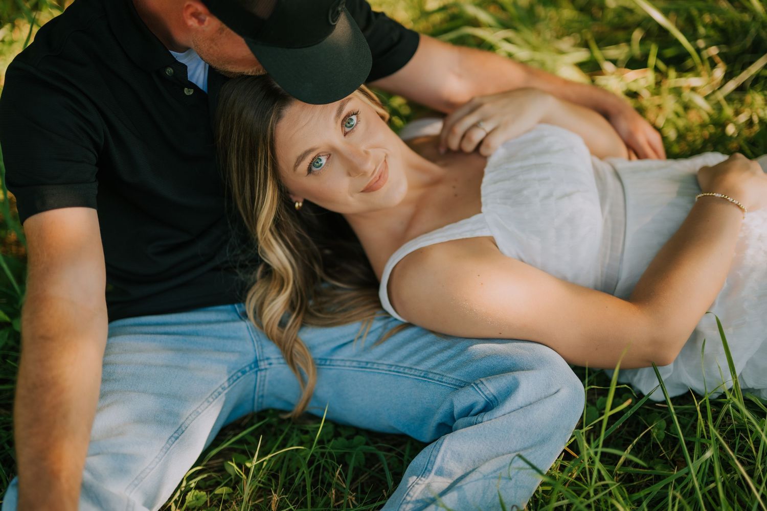 Couple relaxes on grass during outdoor summer photoshoot.