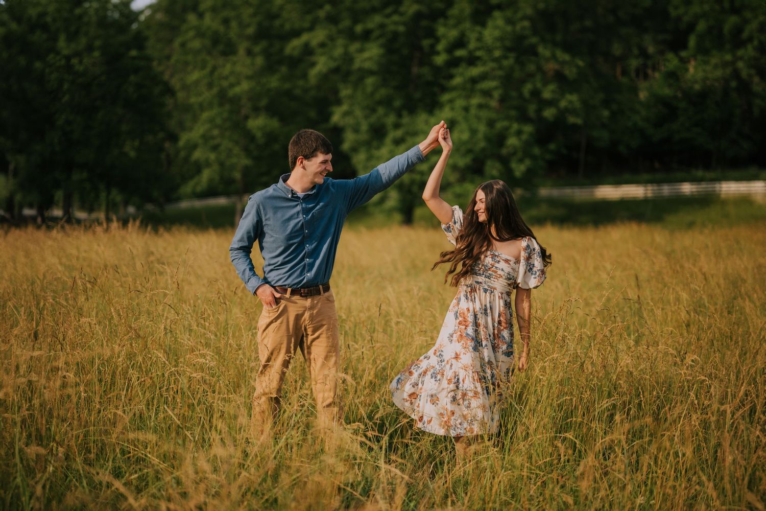 A couple dances and twirls together in a sun-lit meadow.