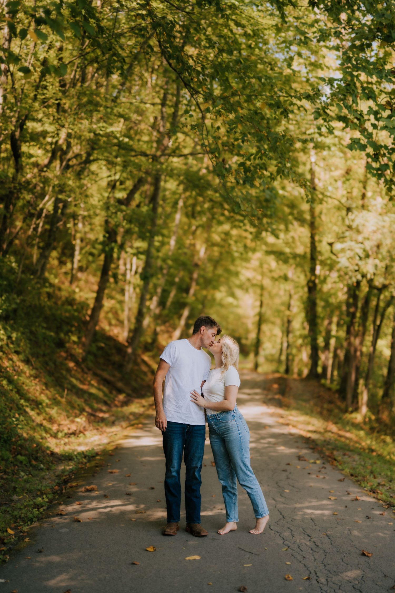 Couple sharing tender moments on a tree-lined path during autumn.