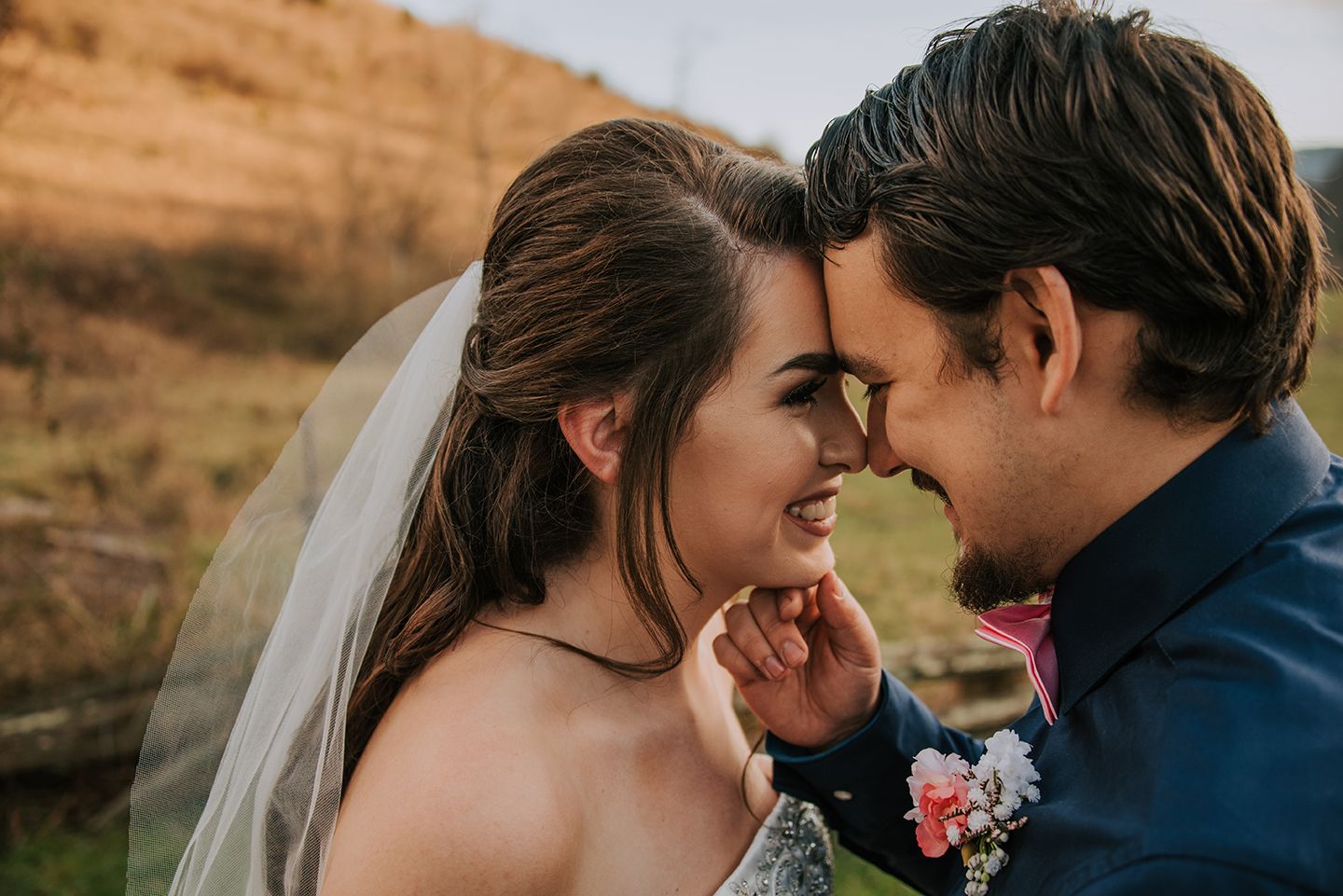 A tender moment between a couple in formal attire against a mountainous backdrop.