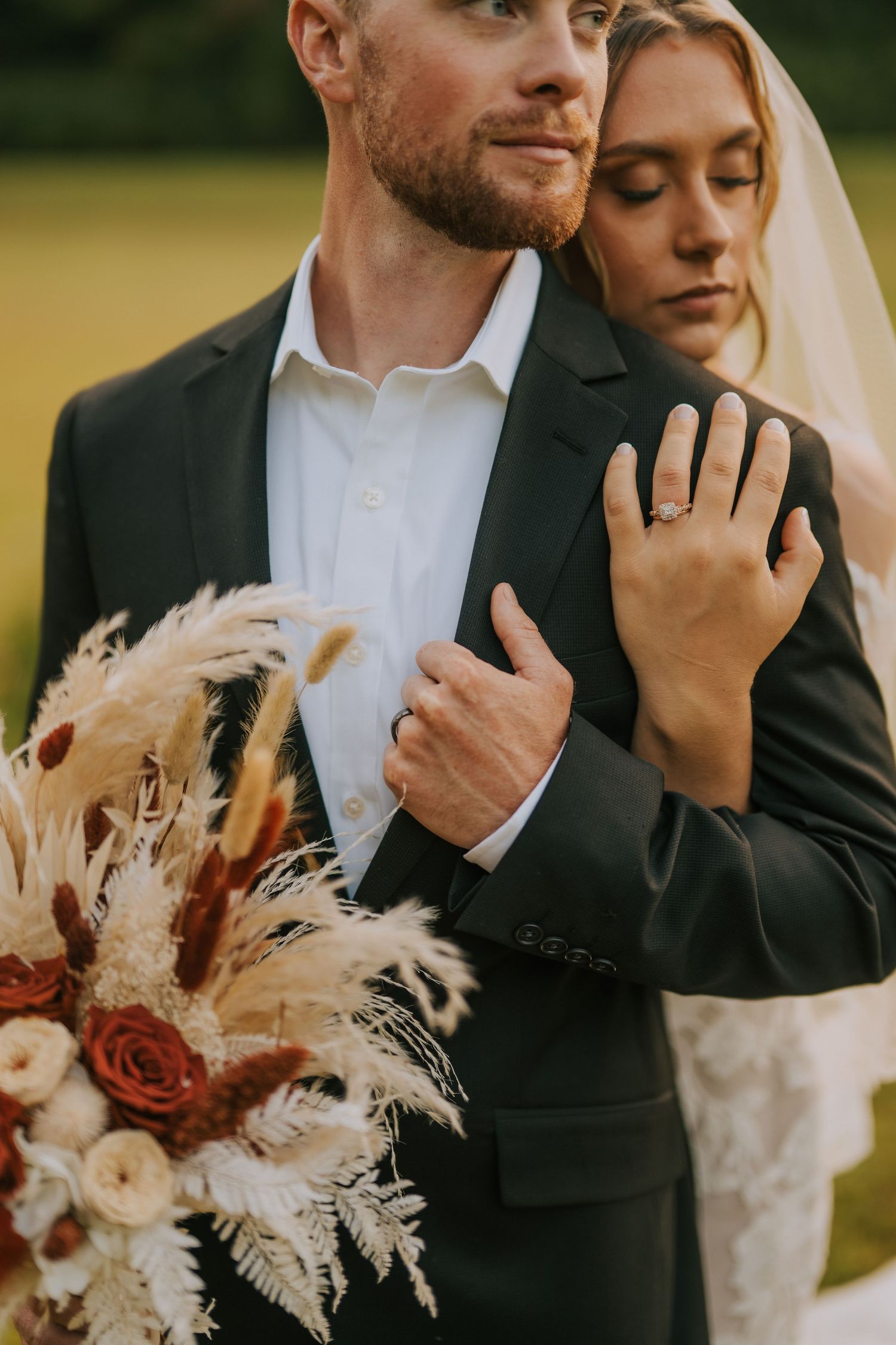 A romantic wedding photoshoot in a field with pampas grass bouquet and elegant attire.