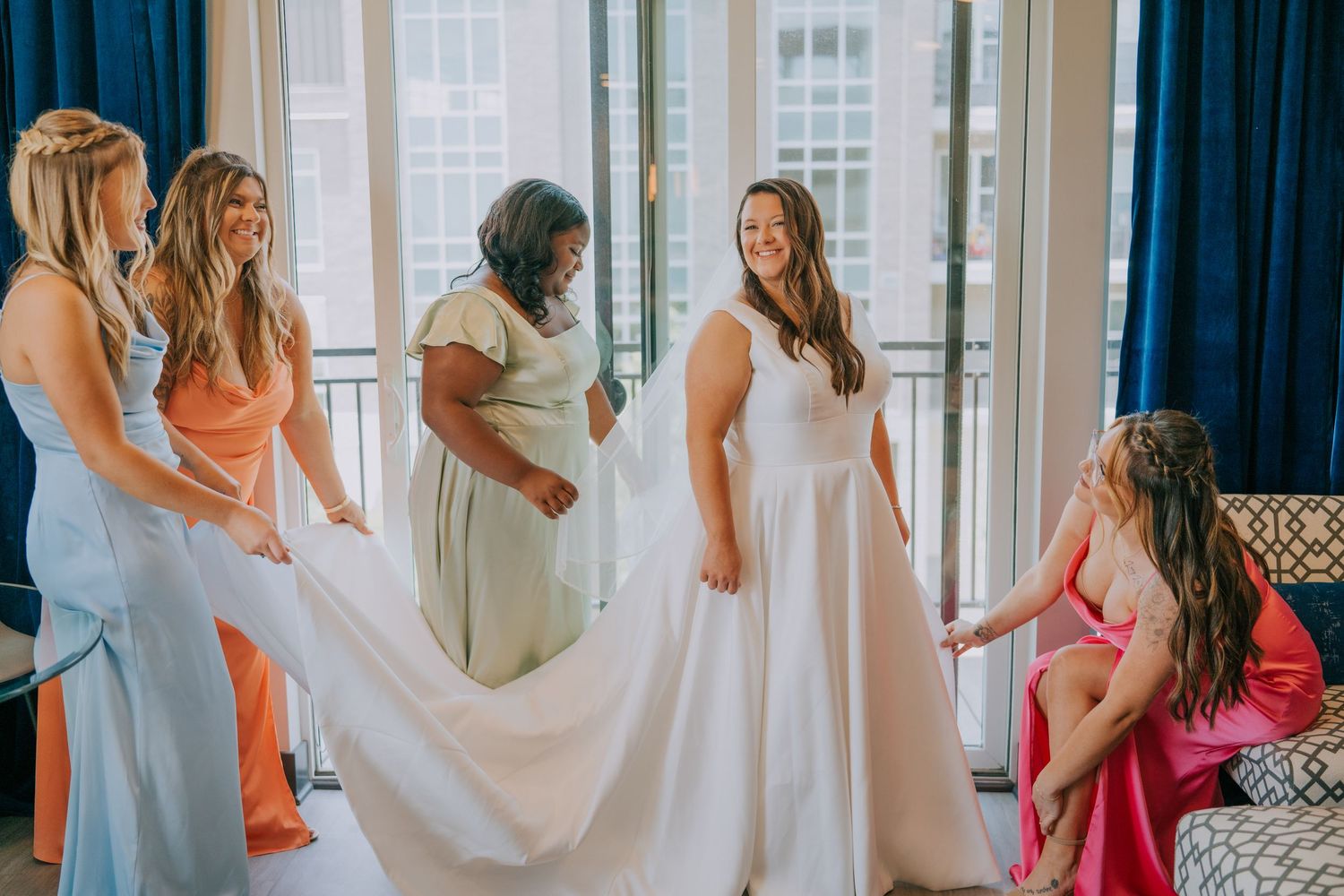 Wedding party getting ready in a bright sunlit room with white robes and dresses.