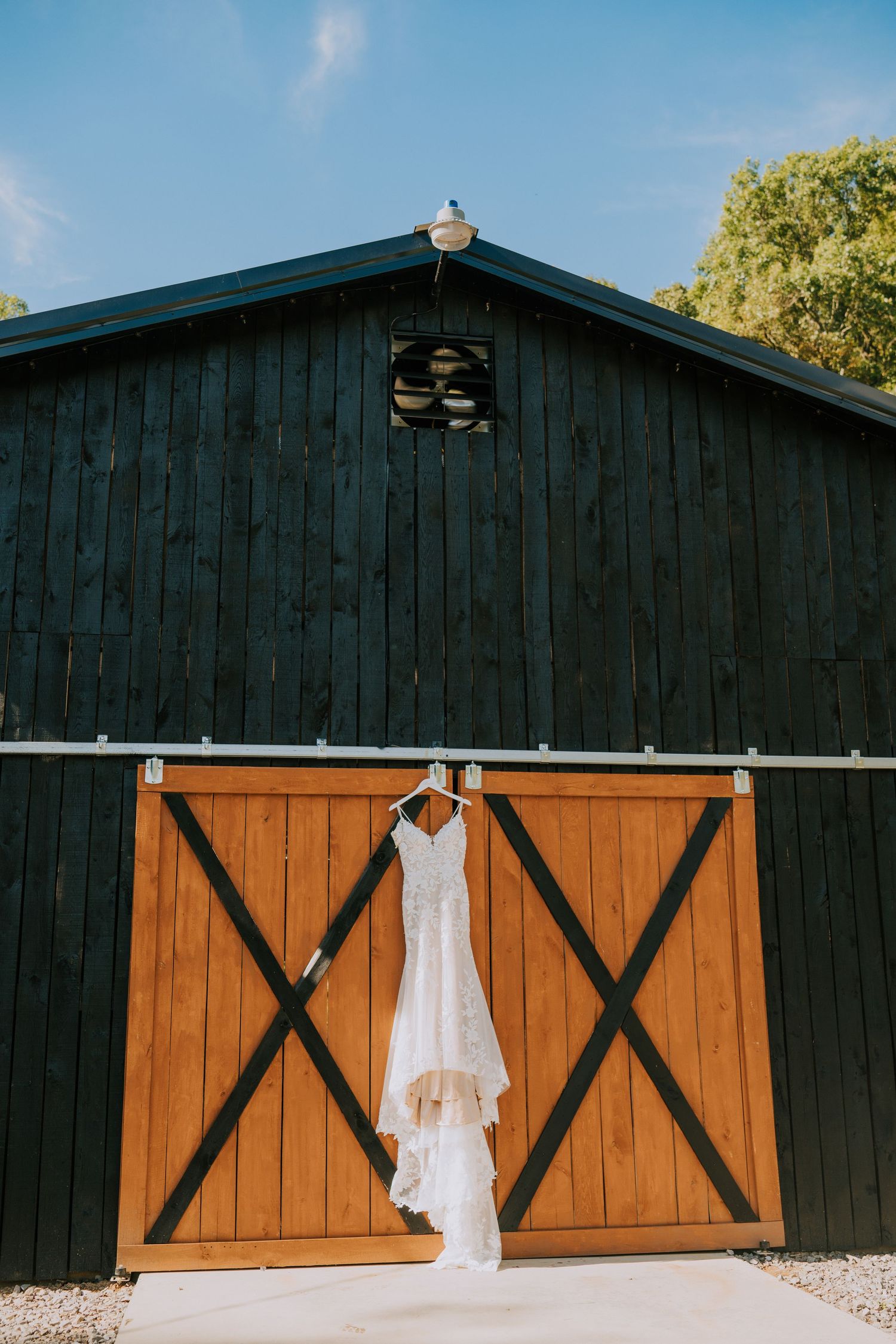 White wedding dress hanging on rustic black and orange barn doors.
