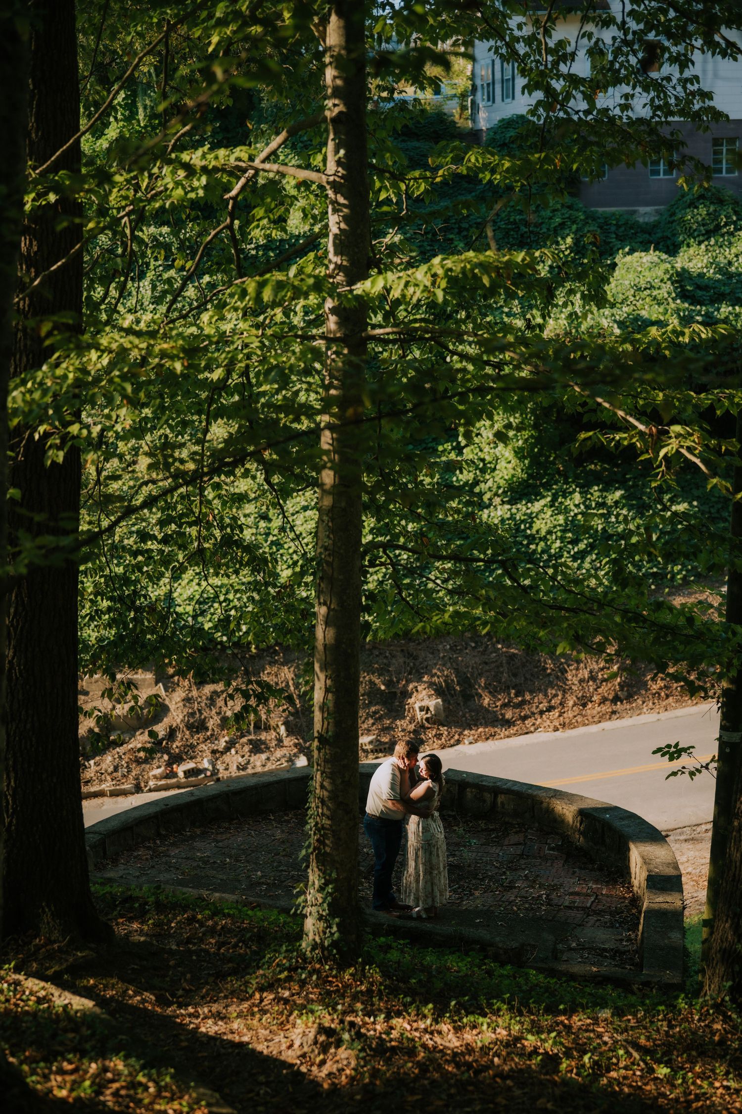A romantic photo session in a wooded park with dappled sunlight filtering through trees.