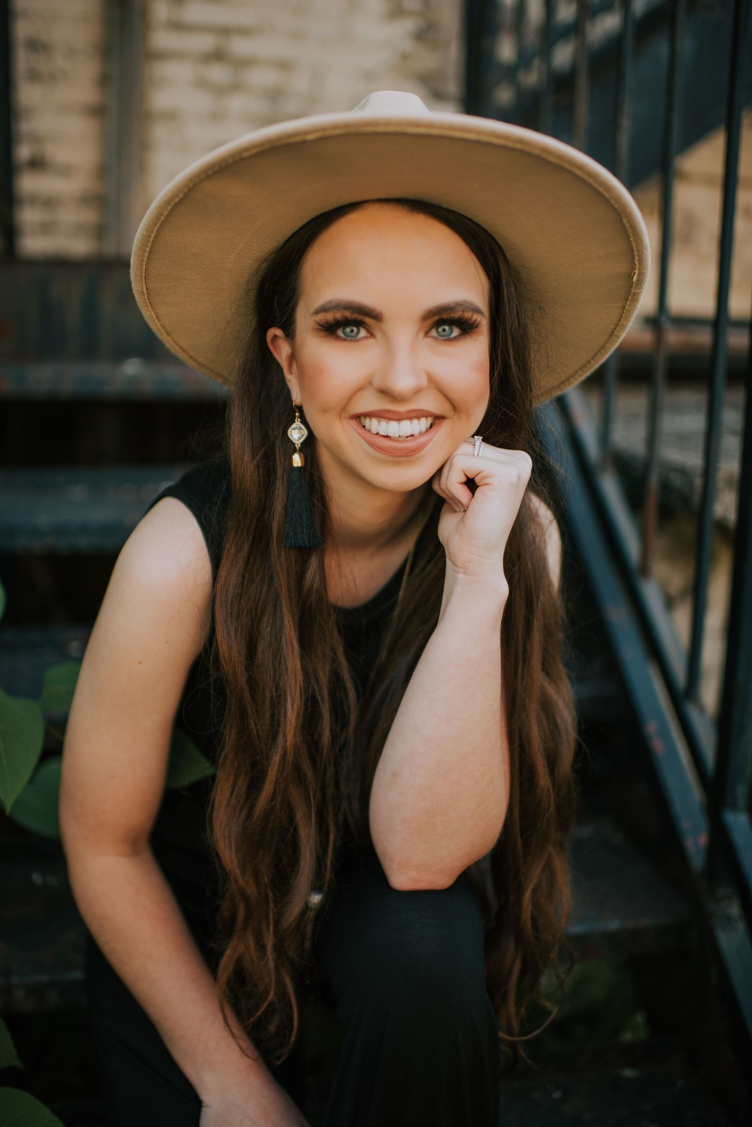 A wide-brimmed hat creates dramatic shadows in an outdoor portrait setting.