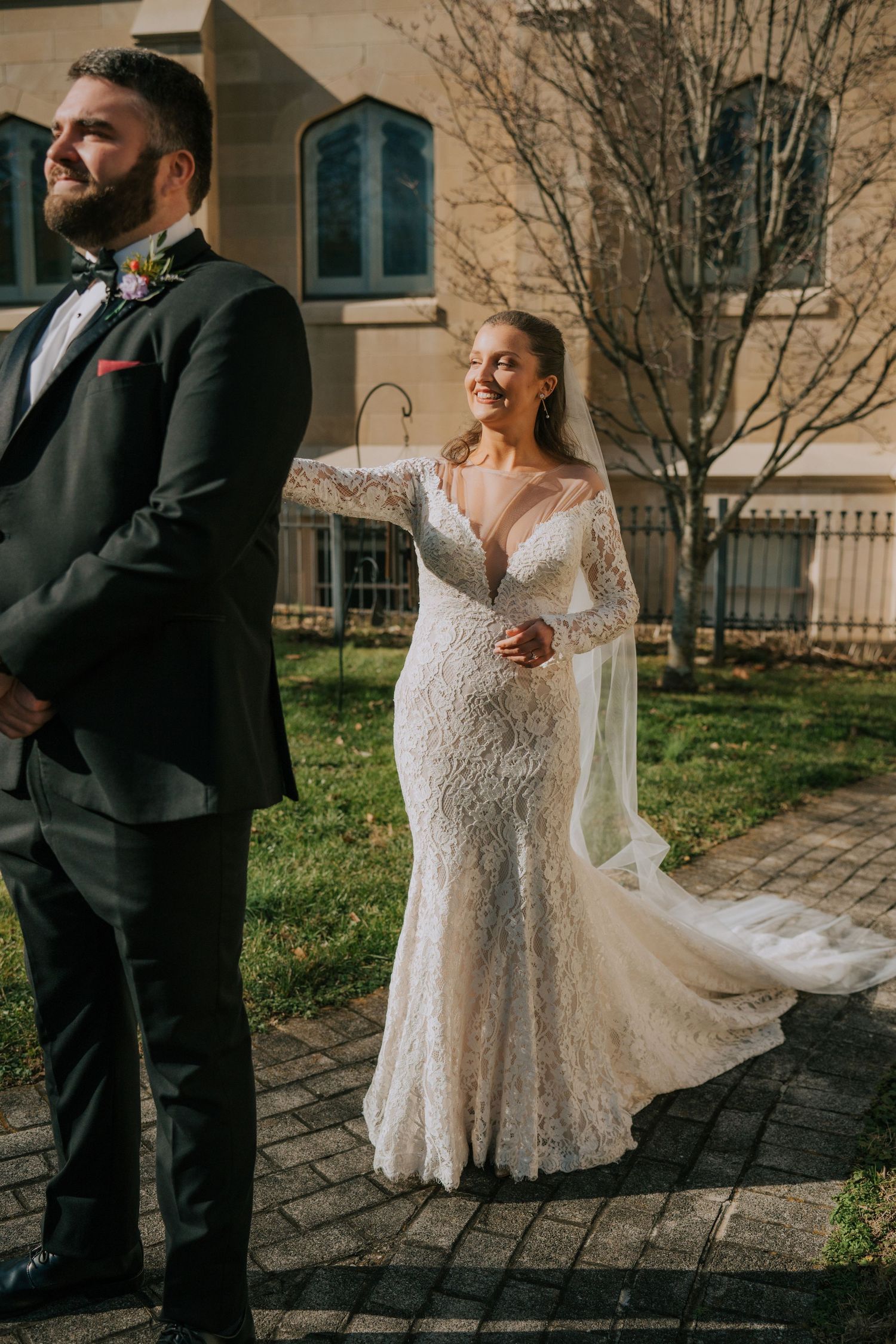 Bride and groom share a first look moment outdoors on stone pavers with church building in background.