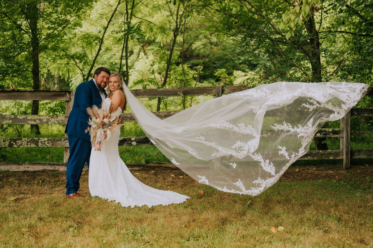 Long flowing wedding veil catches the breeze in a romantic outdoor garden setting.