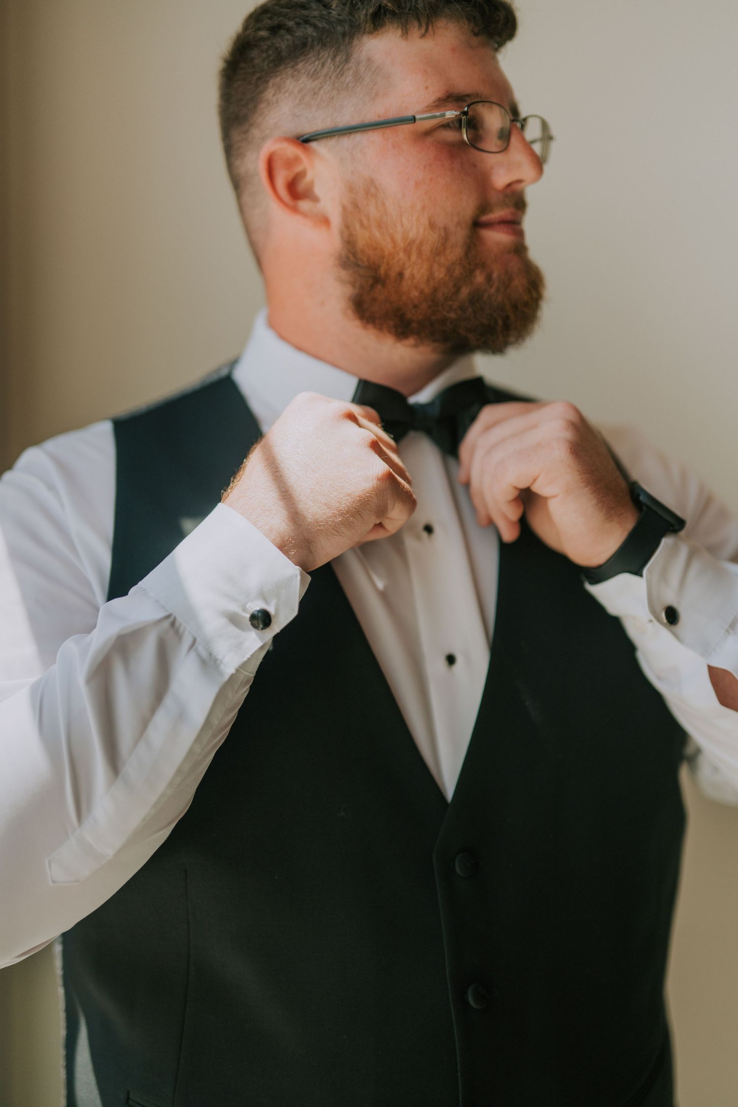 Groomsmen adjusting bow ties and getting ready before ceremony.