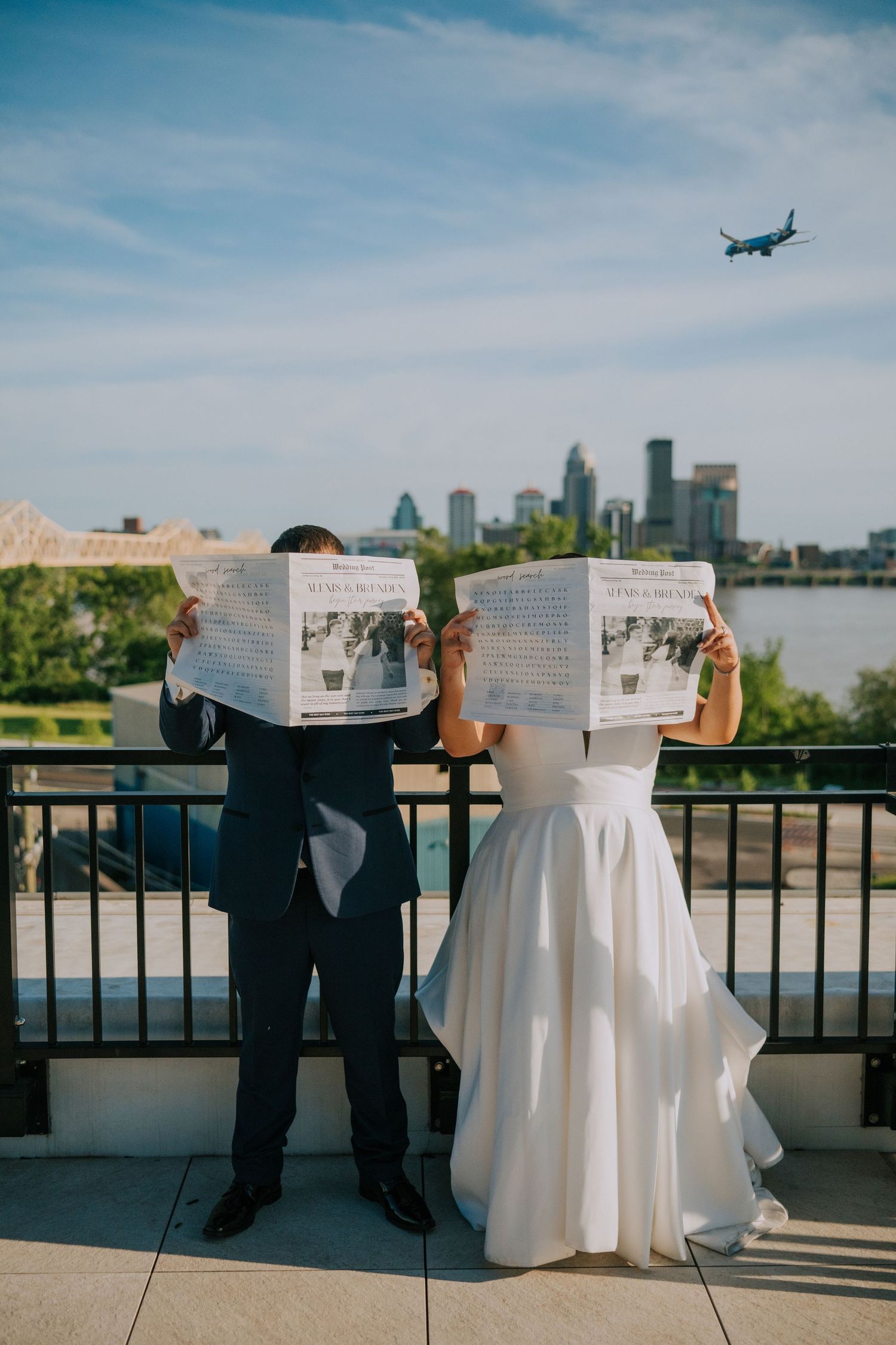 Wedding couple silhouetted against city skyline with planes passing overhead.