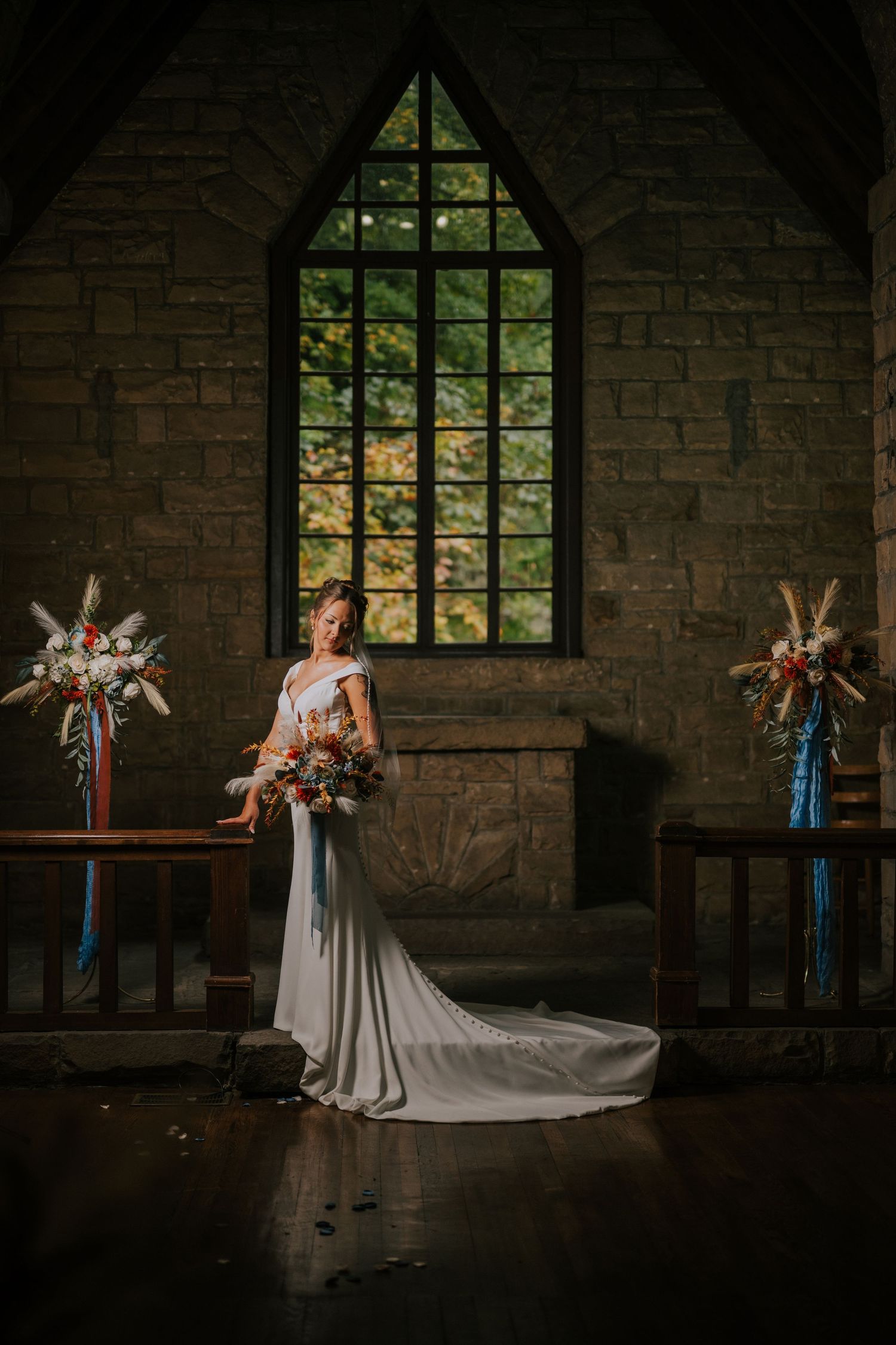 A dramatic wedding photo in a stone chapel with large windows and flowing white dress.