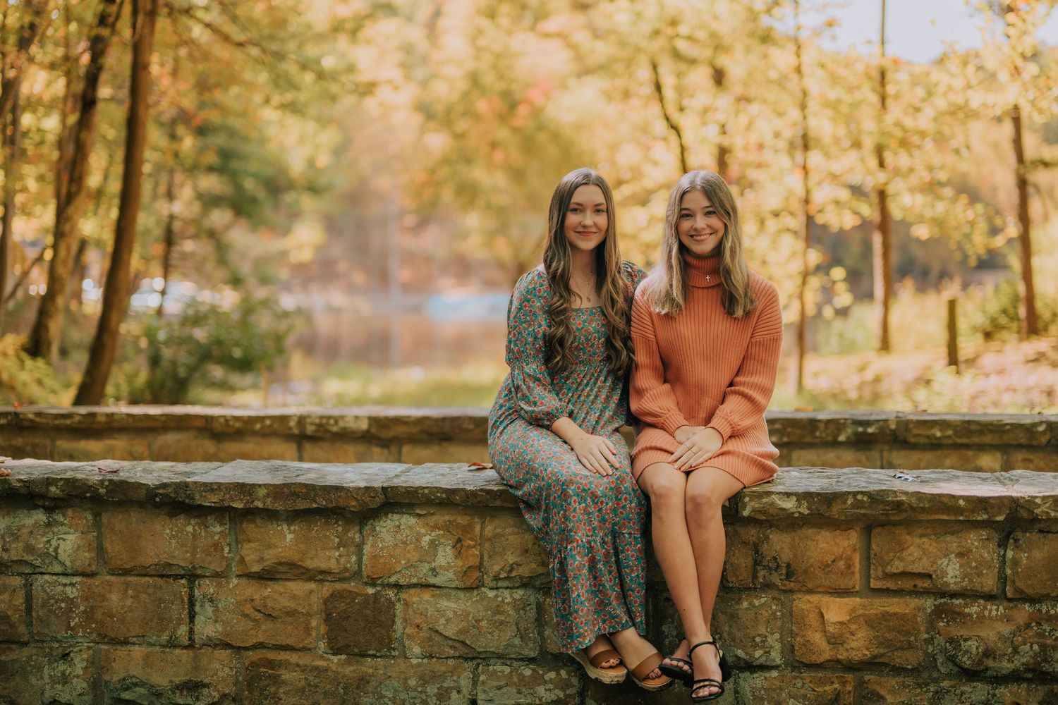 People sit together on rustic stone steps surrounded by autumn foliage.