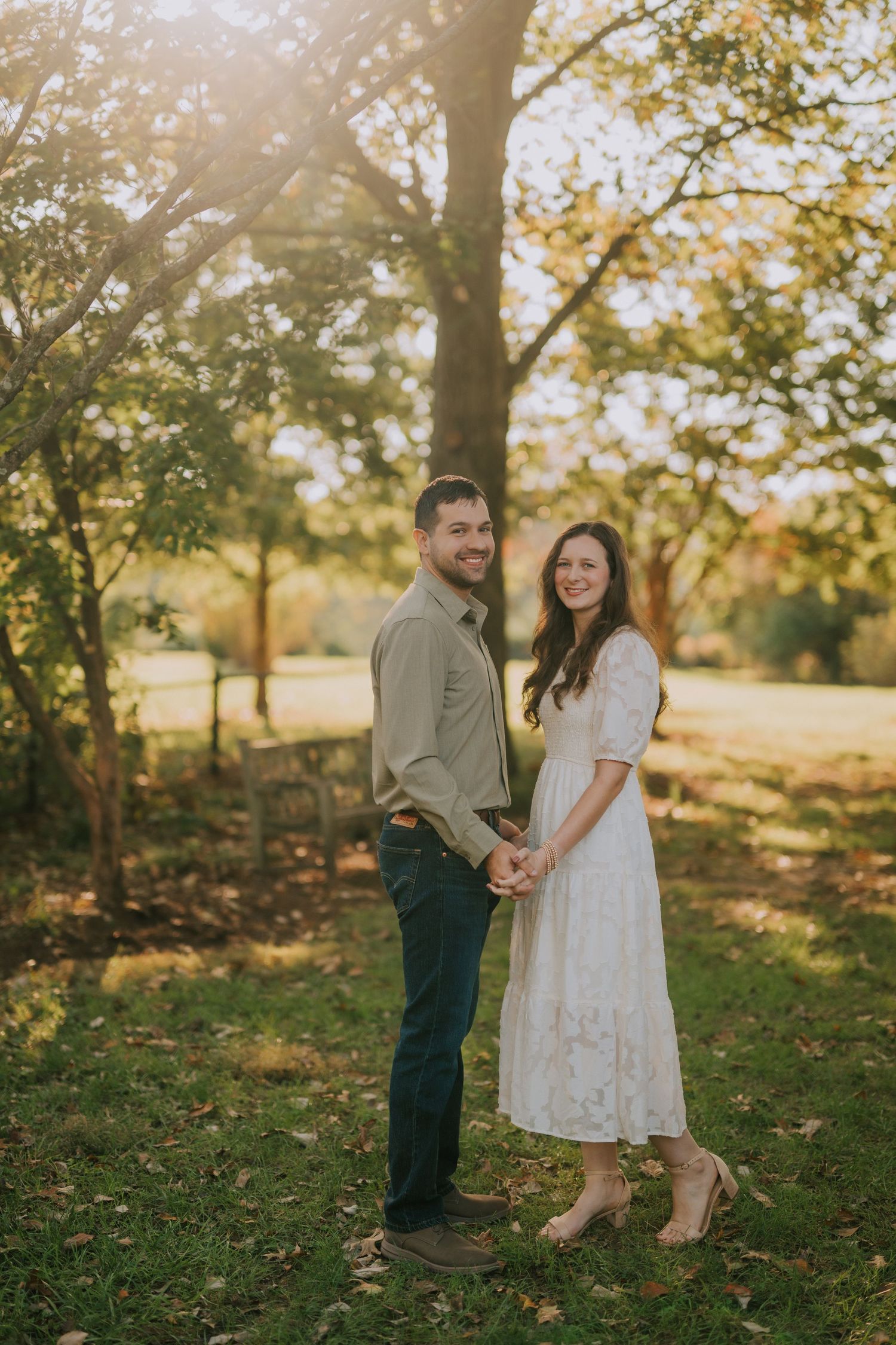 A romantic autumn photoshoot with golden sunlight filtering through trees in the background.