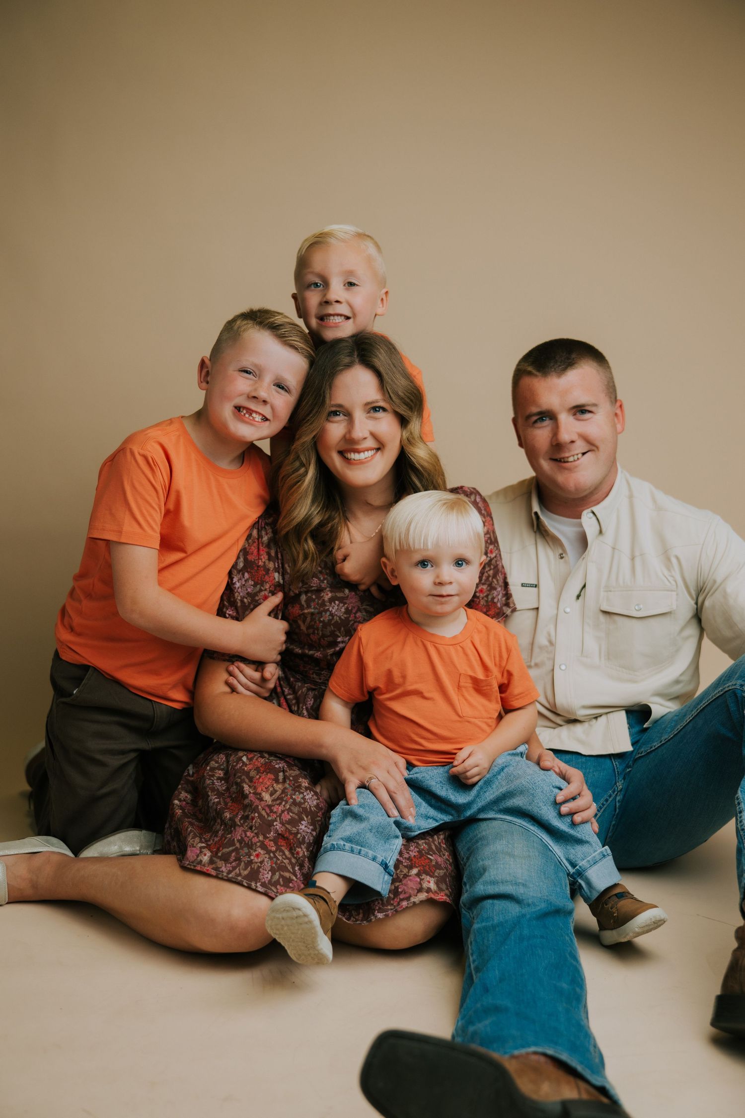 A family portrait session with parents and children wearing coordinated orange and brown outfits.