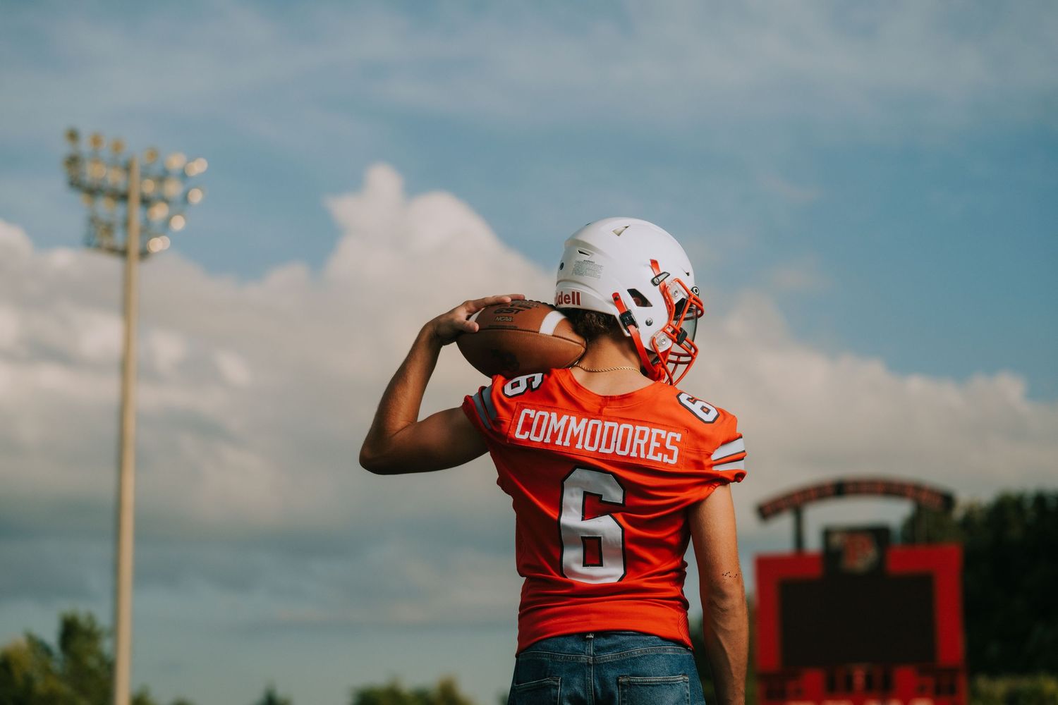 Football players in red and white uniforms practice on sunny field during training session.