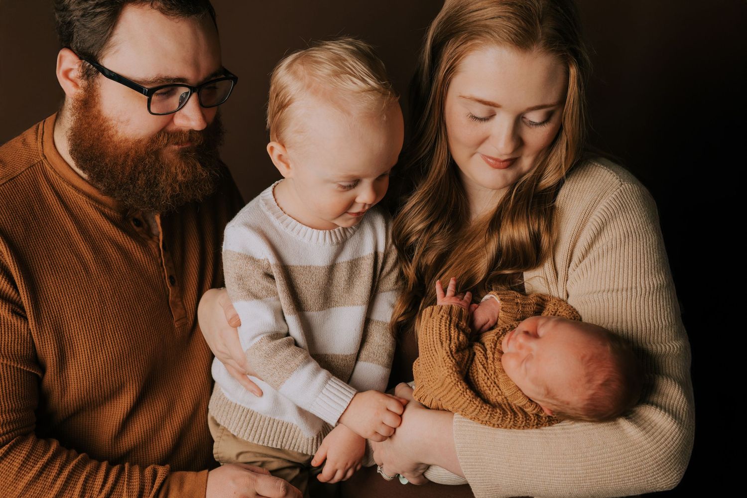 Family portrait in warm tones showing tender moments with a baby.