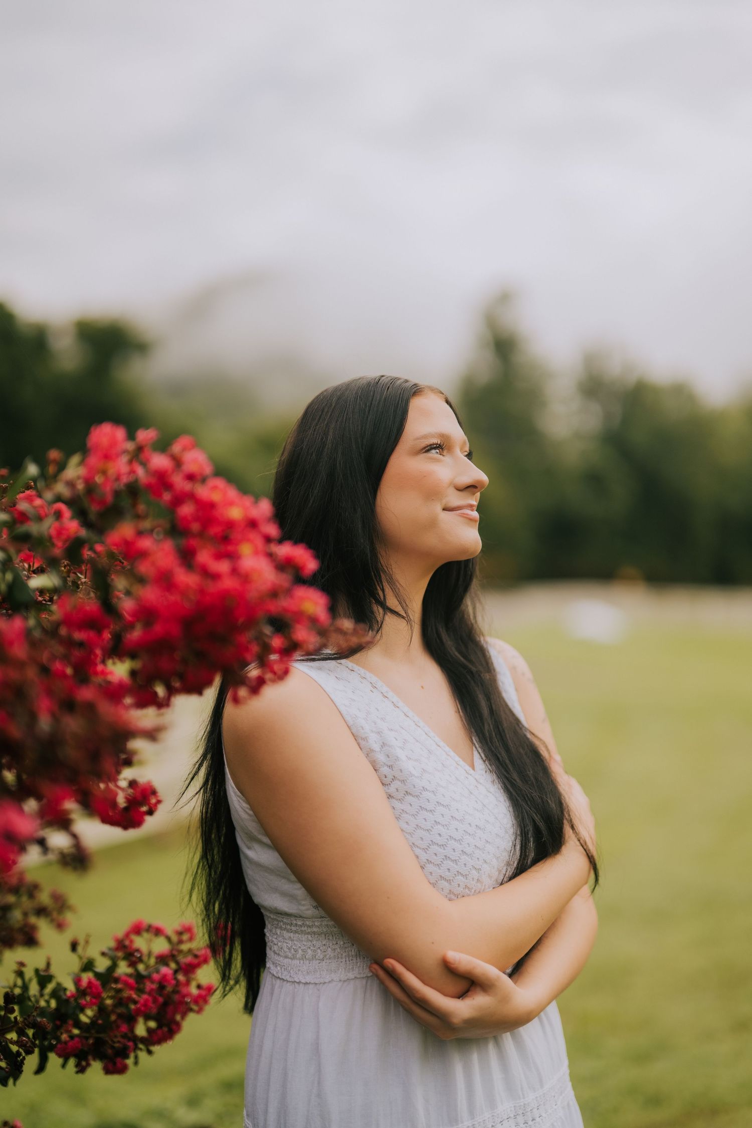 A peaceful portrait next to vibrant red flowers in a garden setting.