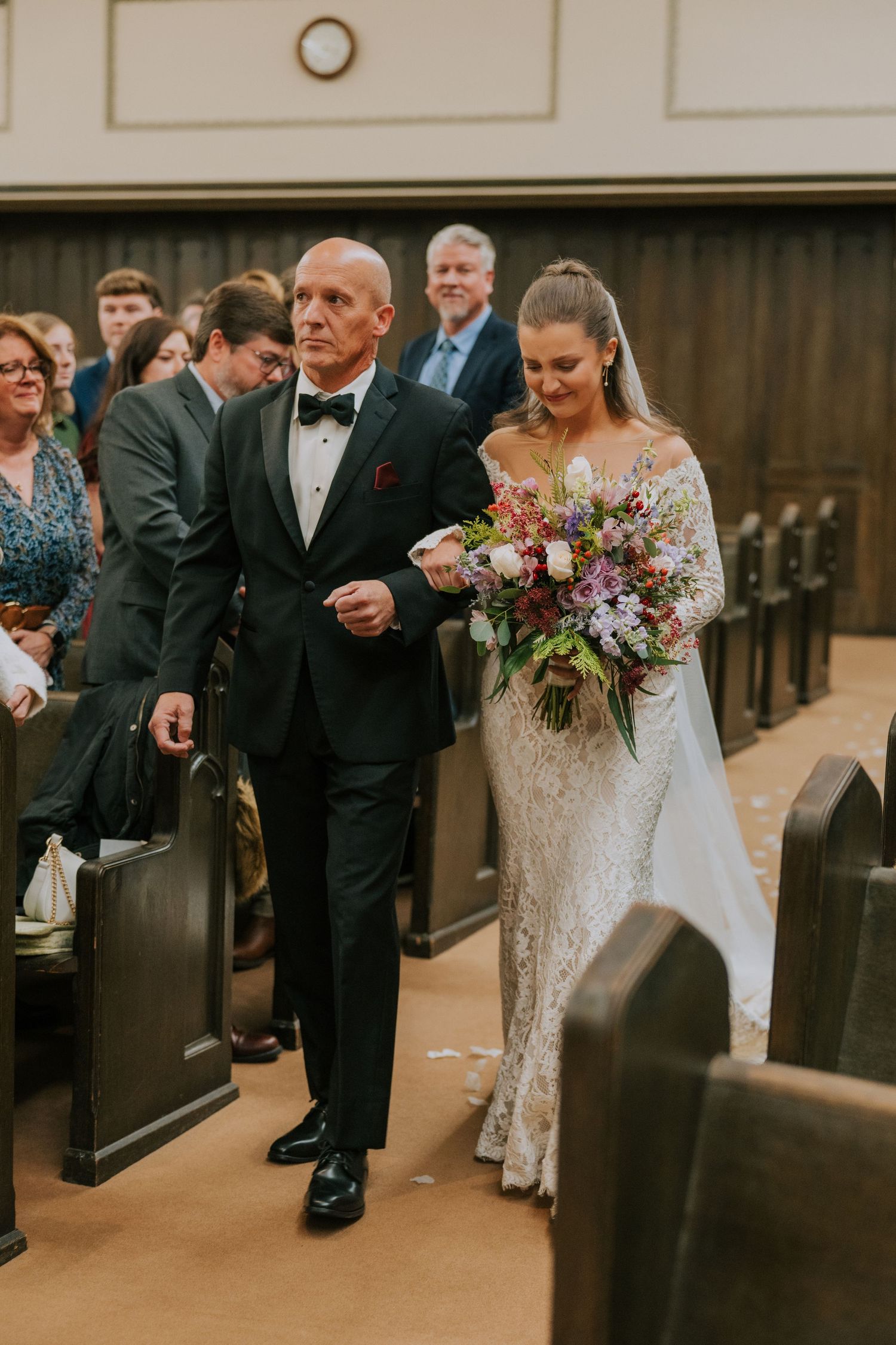 A traditional wedding ceremony in a church with a couple walking down the aisle together while guests look on.