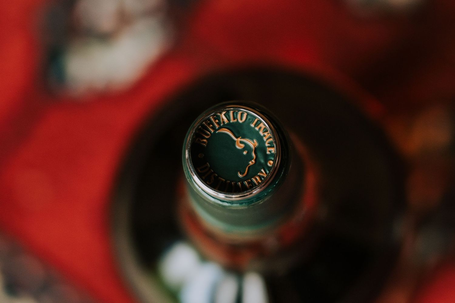 Close-up detail of beer bottle caps with blurred red background.