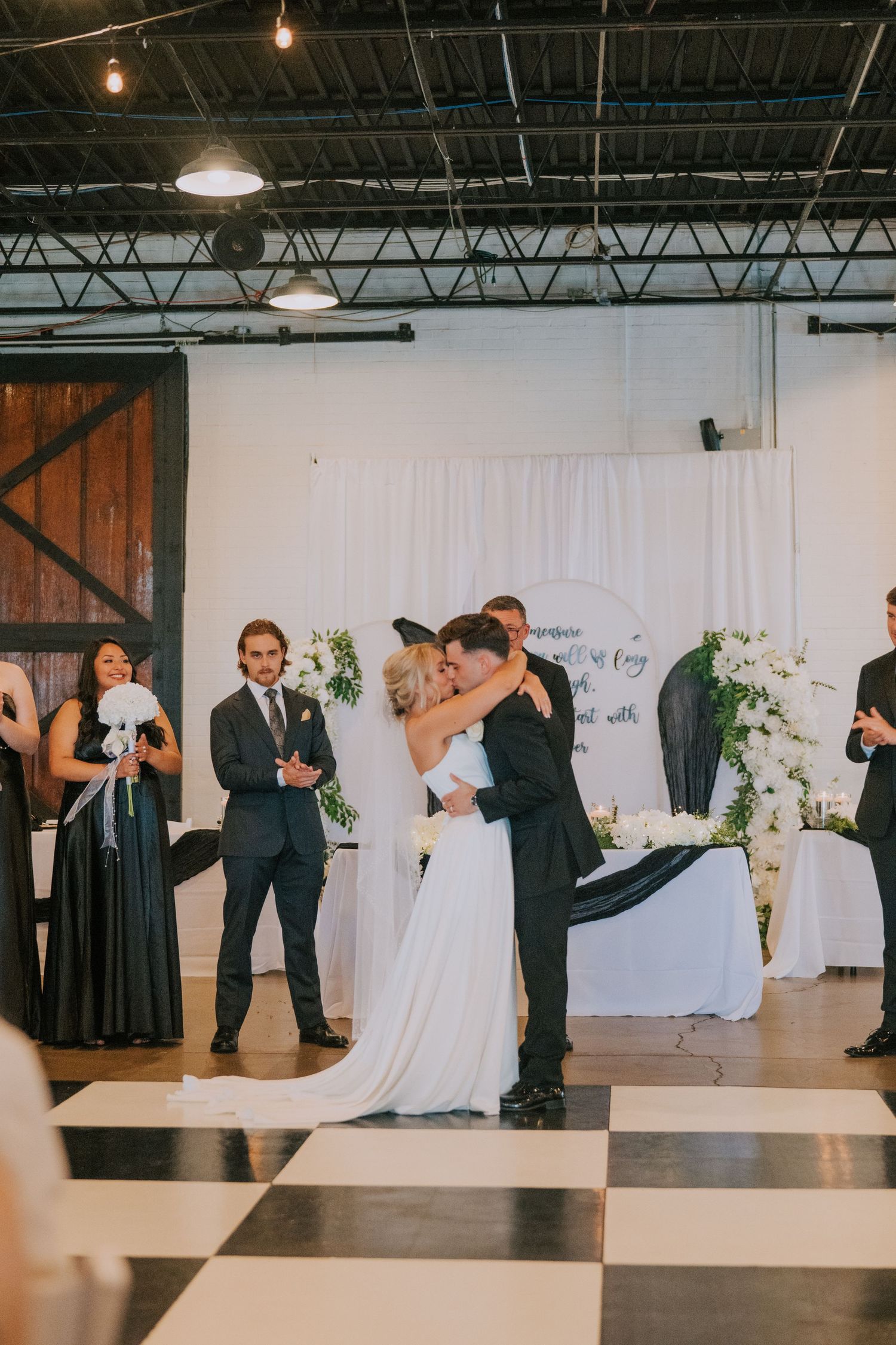 Wedding ceremony sequence in an industrial venue with white draping and hanging lights.